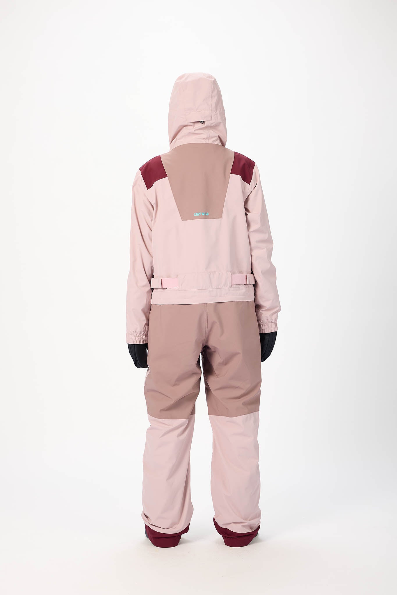 Person wearing a two-tone pink and beige snowsuit on a white background