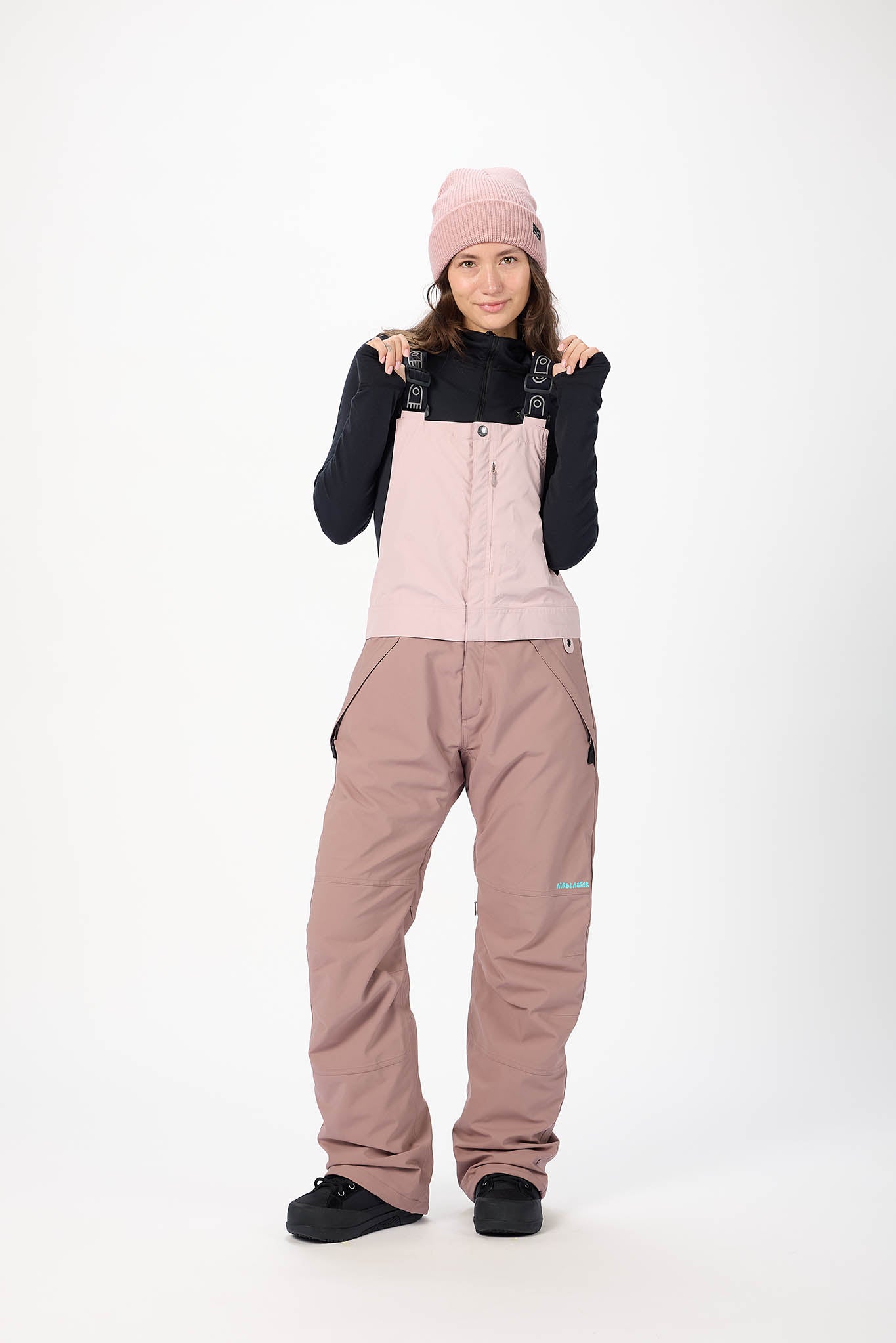 Person wearing a pink snowsuit with a black jacket on a white background