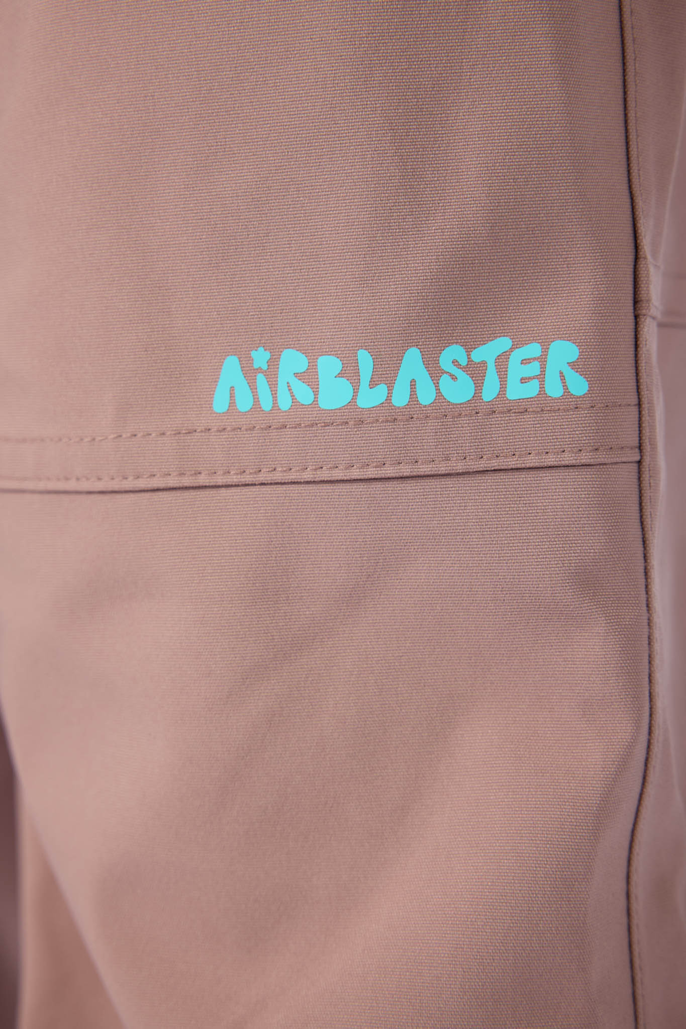 Close-up of a brown jacket with 'Airblaster' logo in blue.