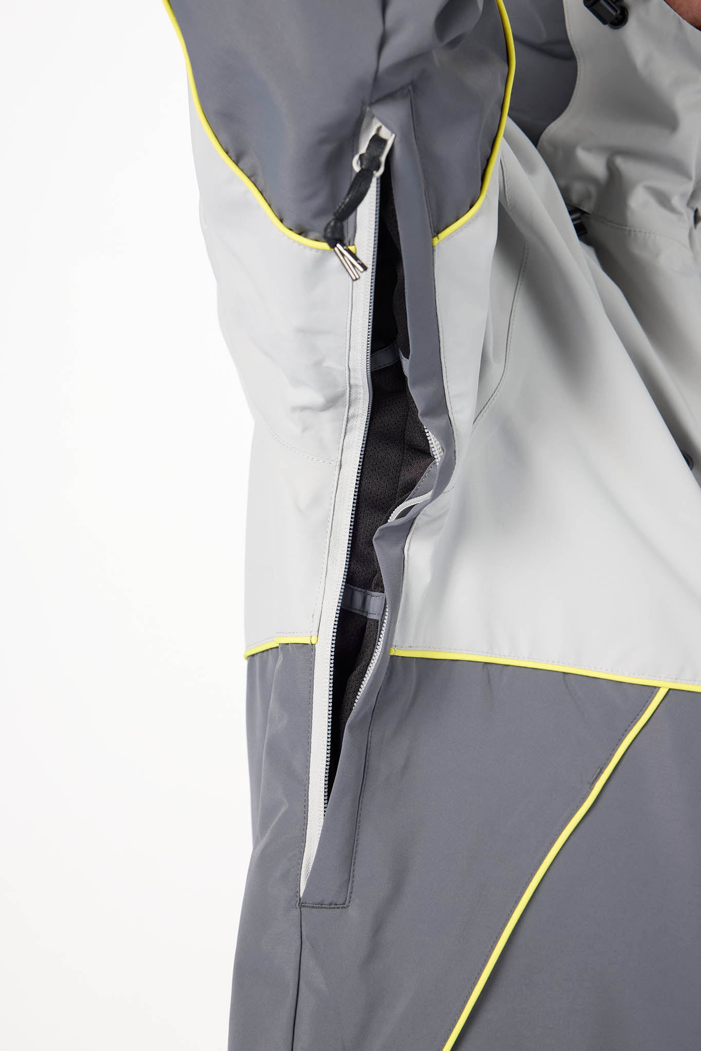 Close-up of a gray and light gray outdoor jacket with bright yellow piping and a vertical zipper detail, shown against a plain white background. 