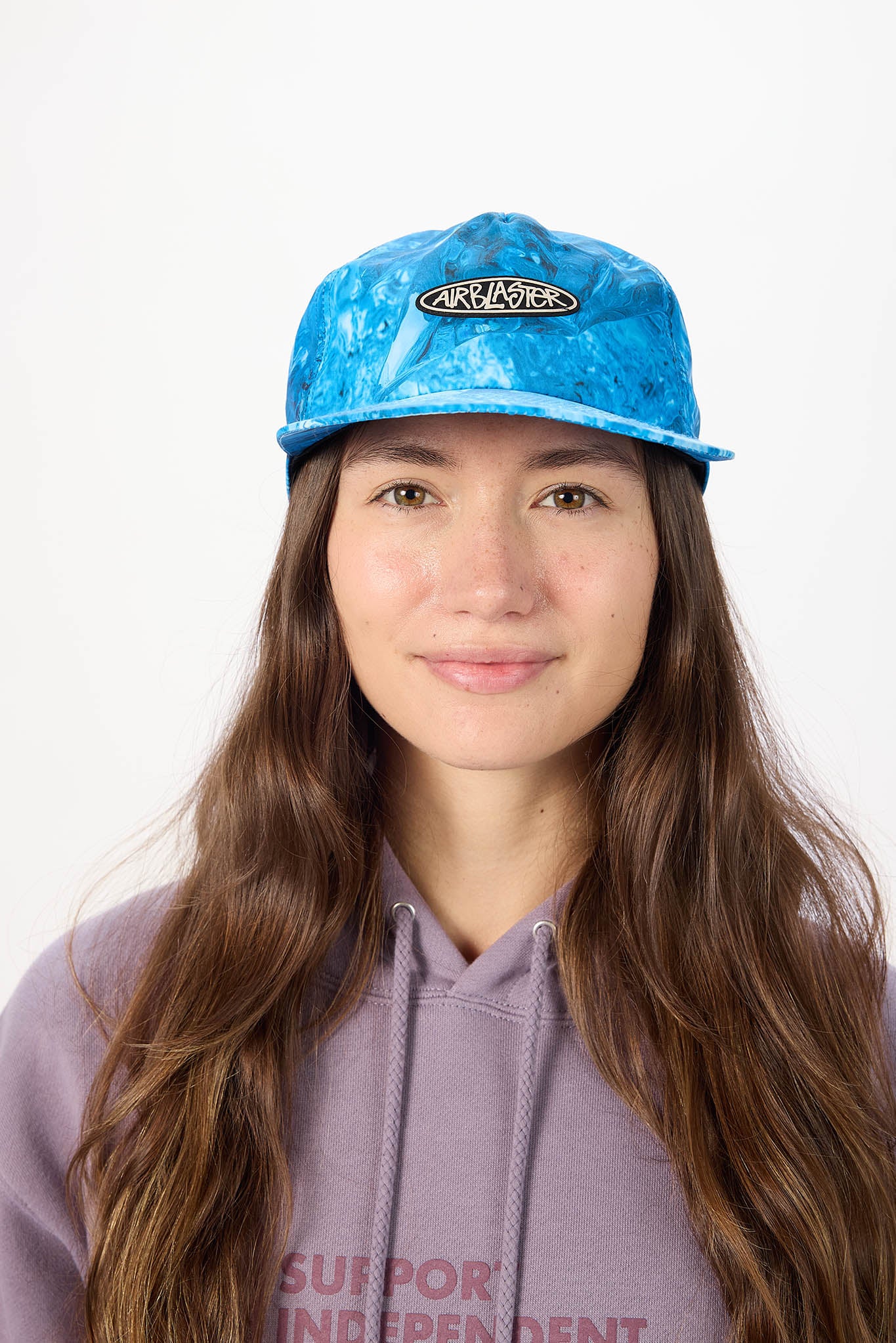 A woman with long brown hair wearing a blue marbled baseball cap