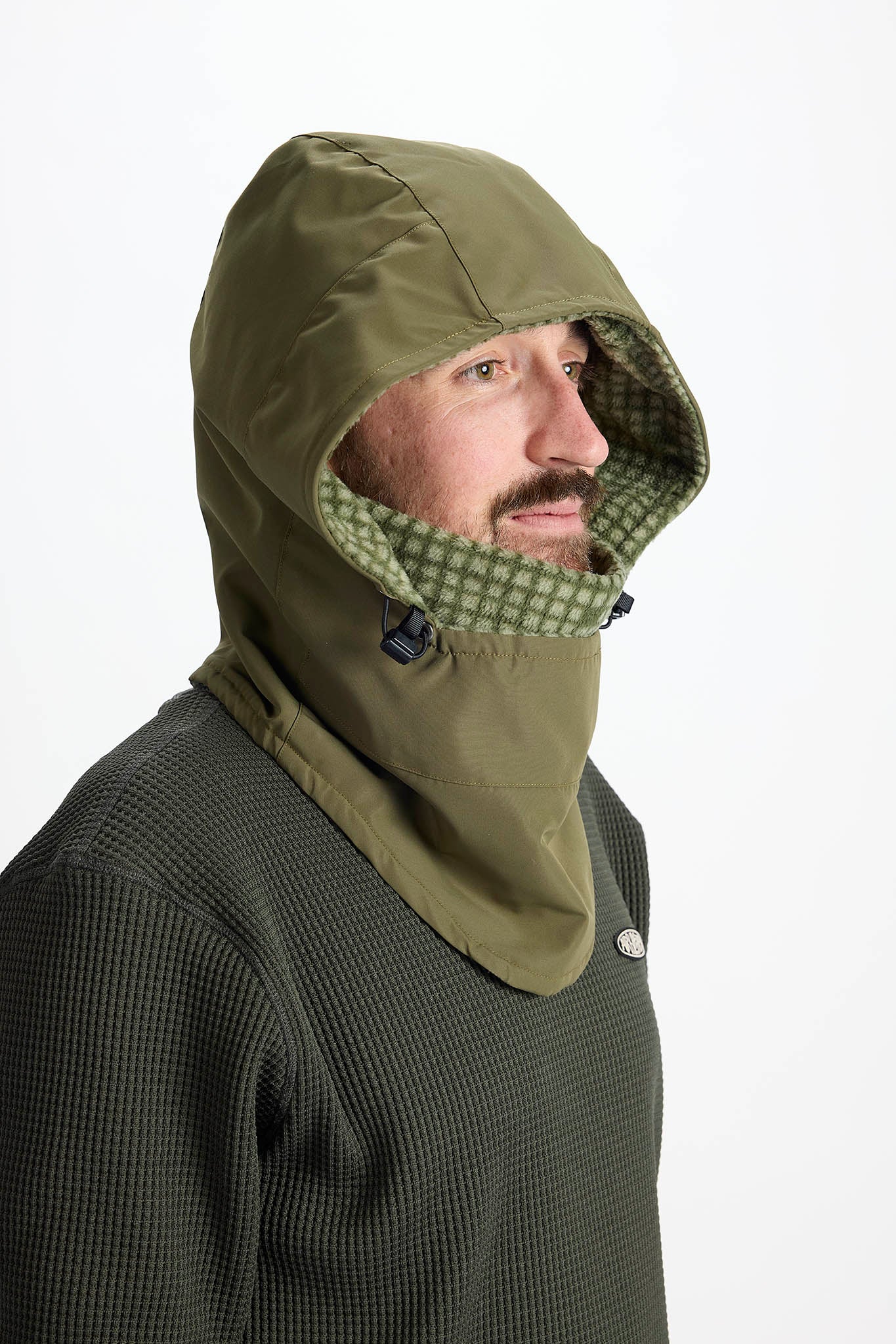 A man wearing an olive green hooded neck warmer balaclava