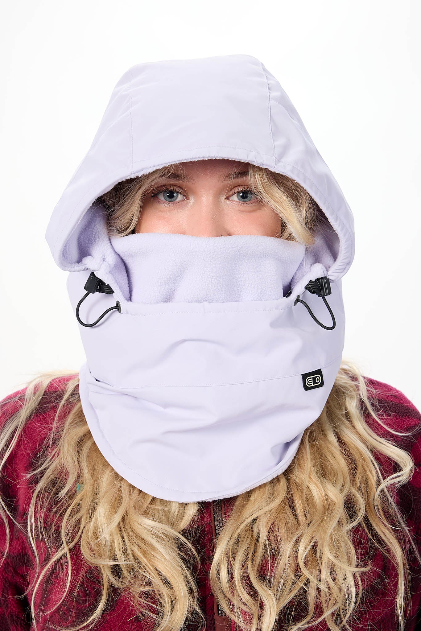 A close-up of a person wearing a light lavender hooded face mask with integrated chin strap and black drawcord loops, shown against a plain white background.