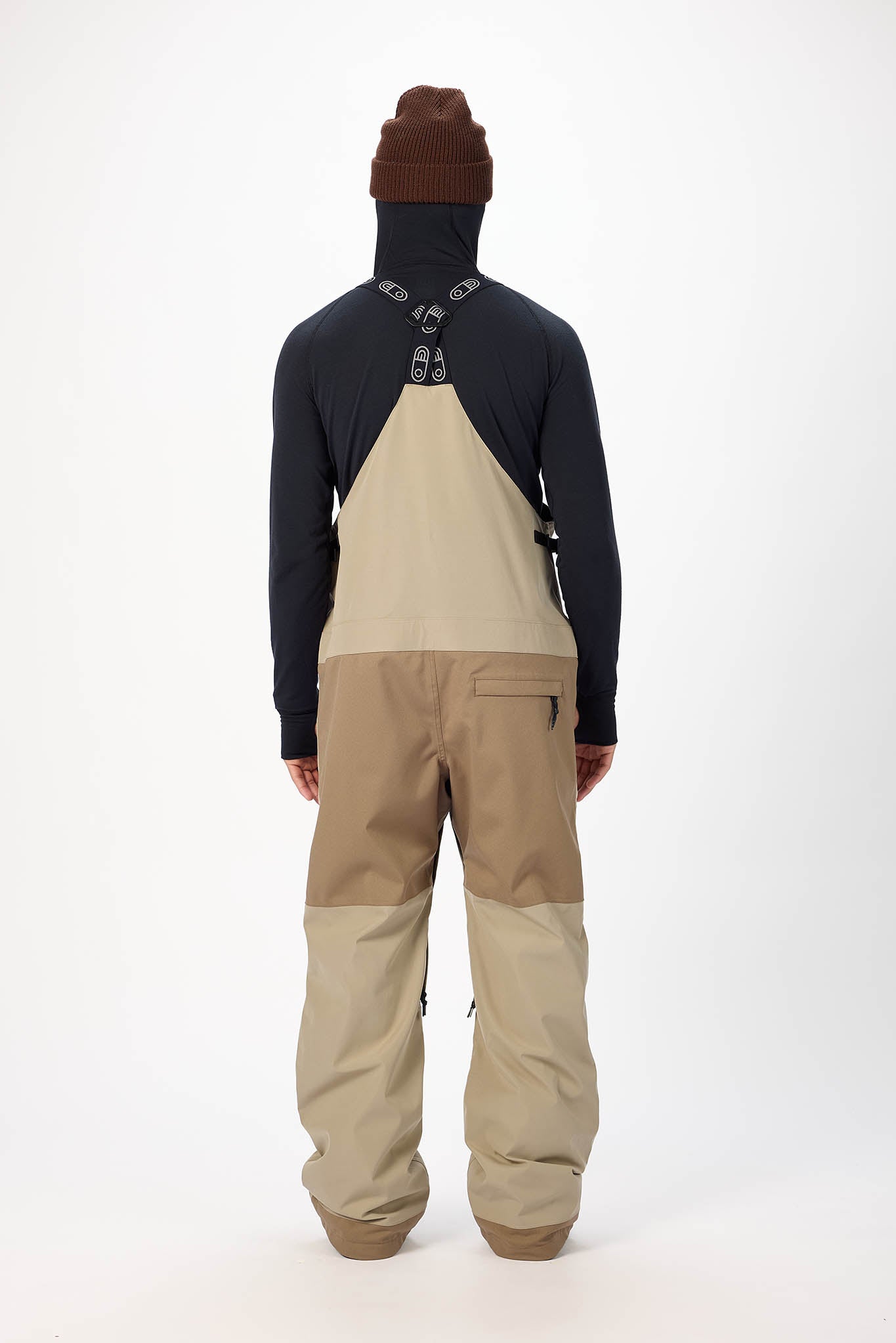 Person wearing a black and beige snowmobile suit on a white background