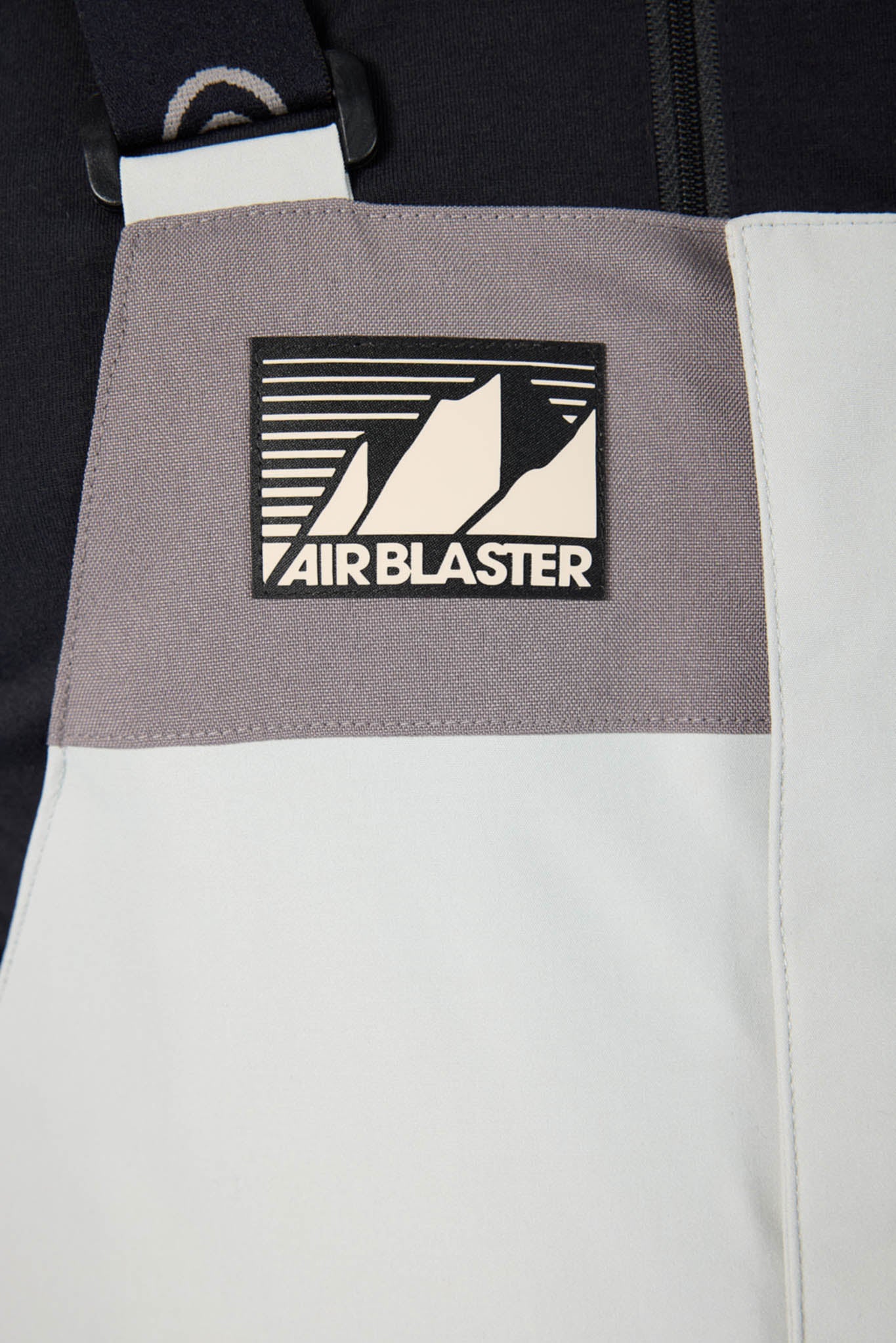 Close-up of a backpack with an Airblaster logo on a gray and white background