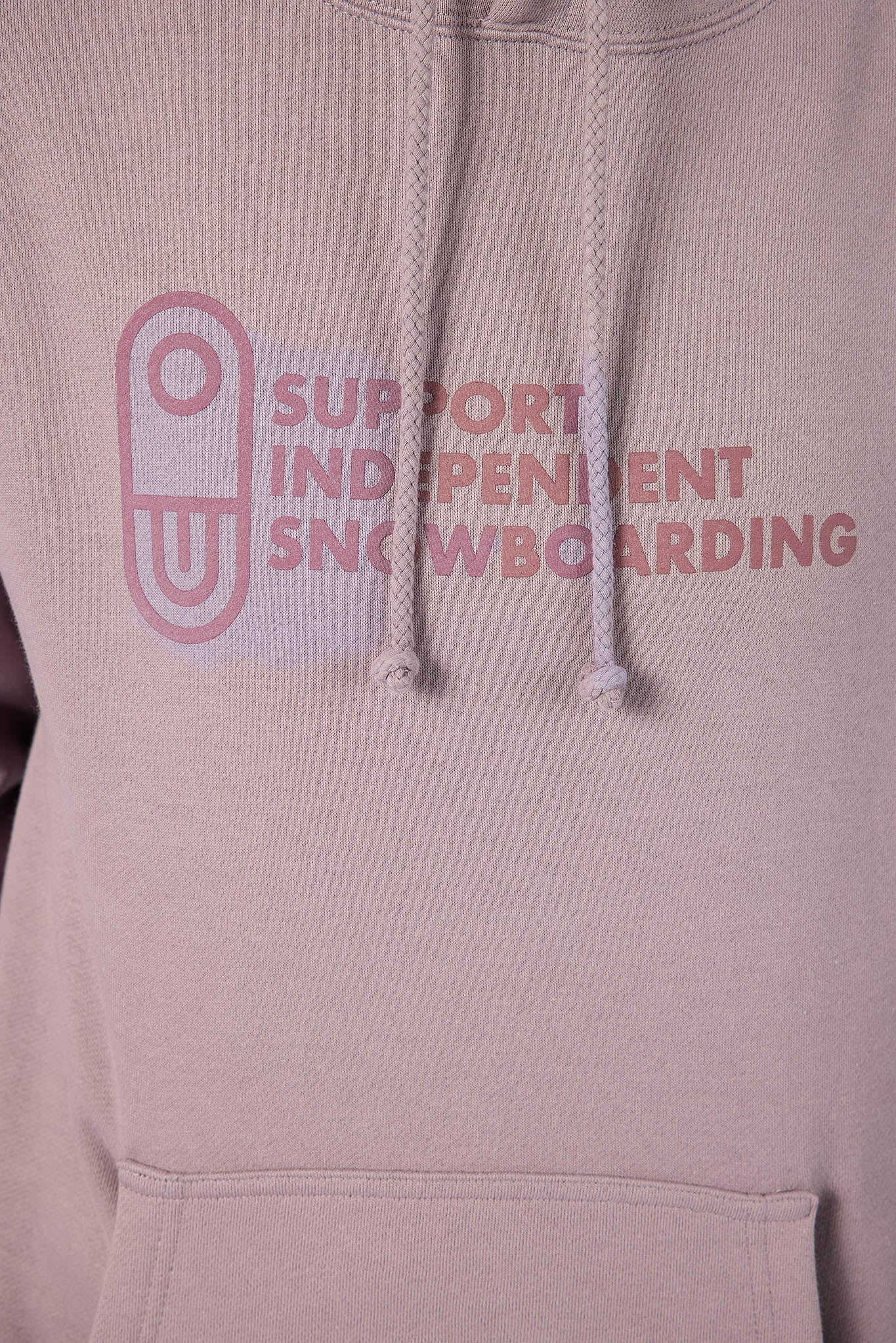A close-up of a light pink hoodie featuring a front graphic that reads 'SUPPORT INDEPENDENT SNOWBOARDING' in pink text next to a pink snowboard outline, with matching drawstrings.