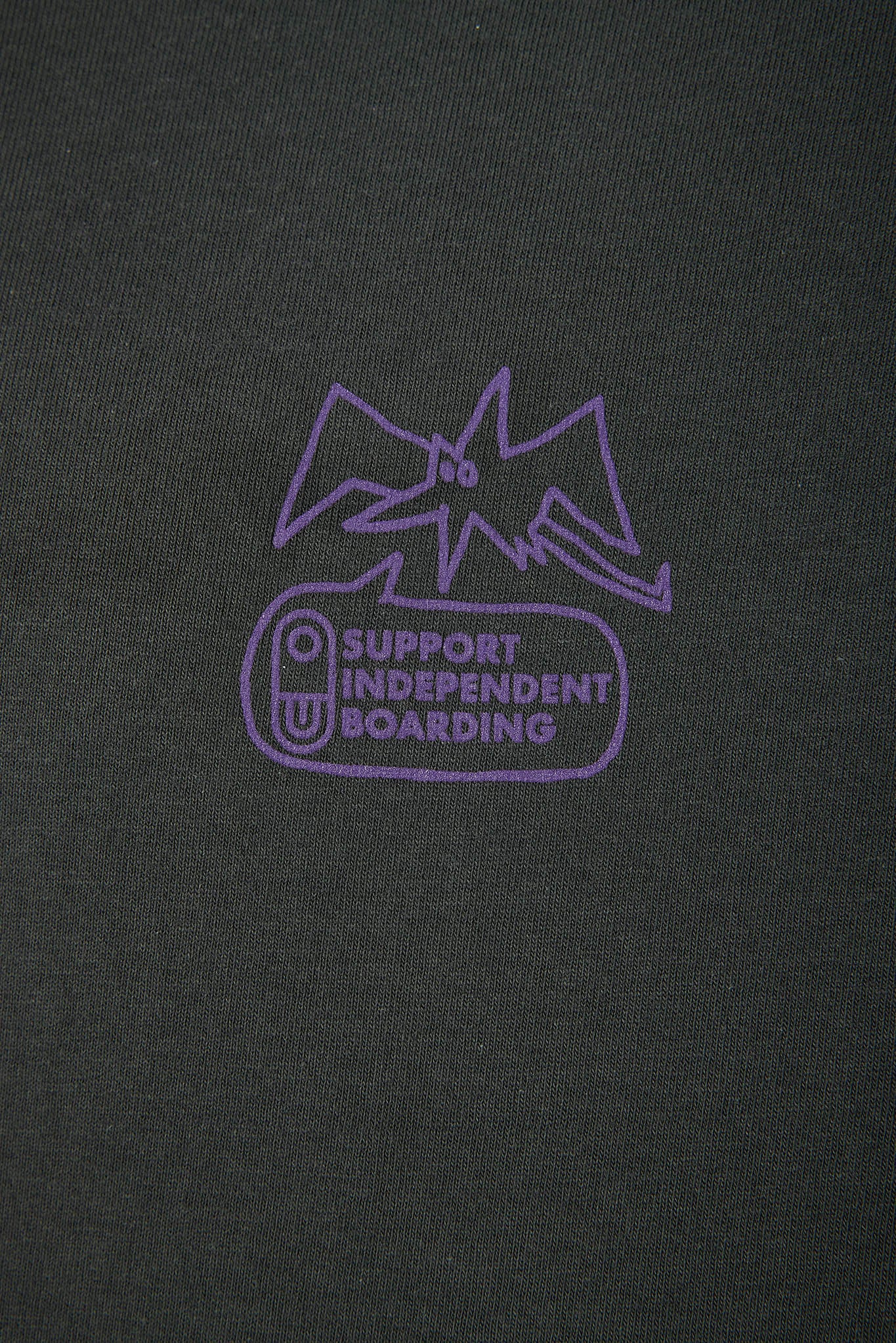 Close-up of a dark charcoal gray fabric with a purple screen-printed graphic that reads 'SUPPORT INDEPENDENT BOARDING' beneath a stylized outline.