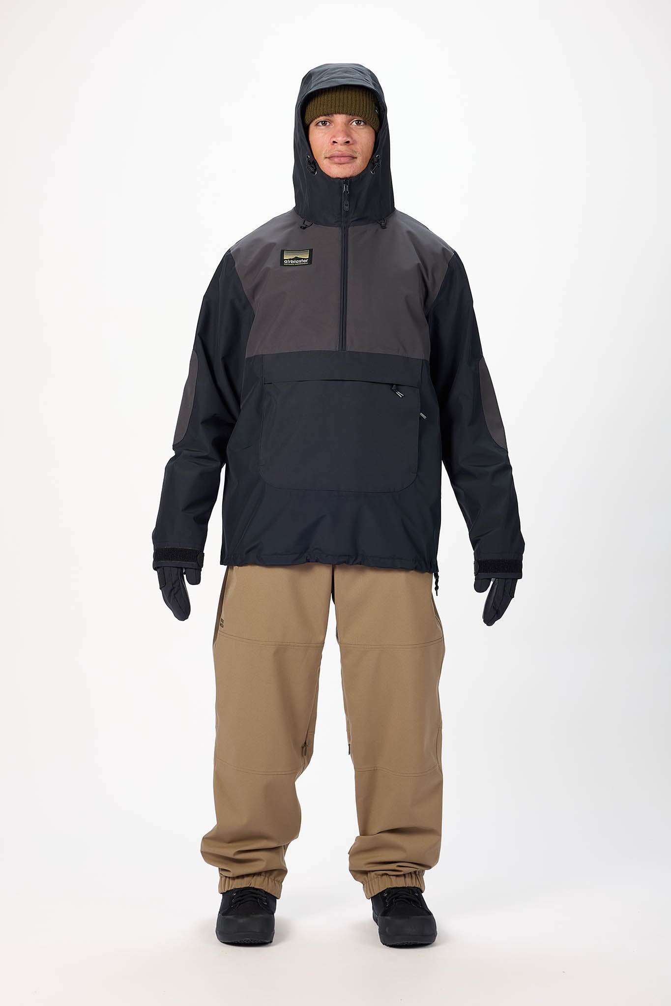 Person wearing a black and gray jacket with a hood and beige pants on a white background