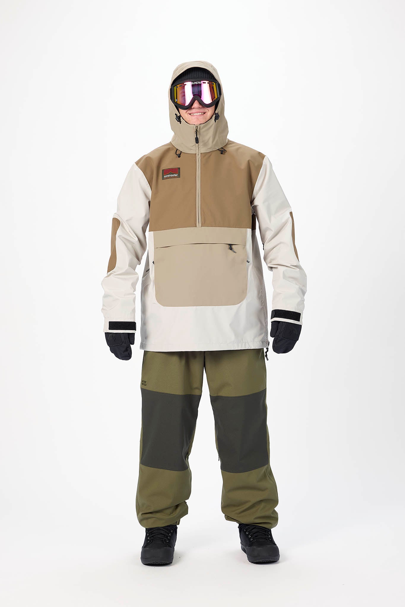 Person wearing a beige and green snowsuit with goggles on a white background