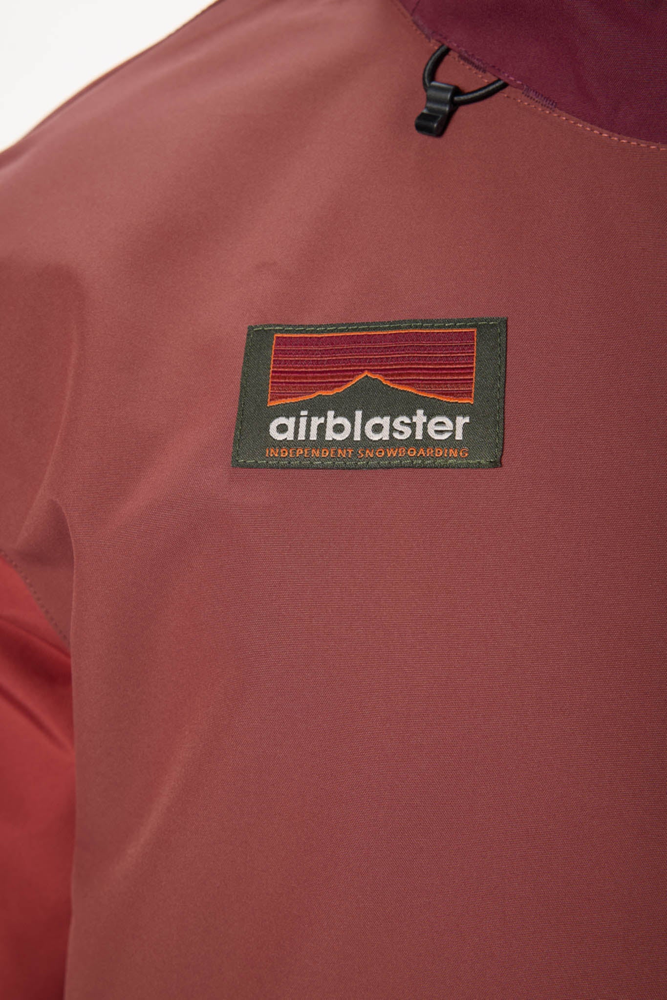 Close-up of a maroon jacket with an 'airblaster' logo on the chest.
