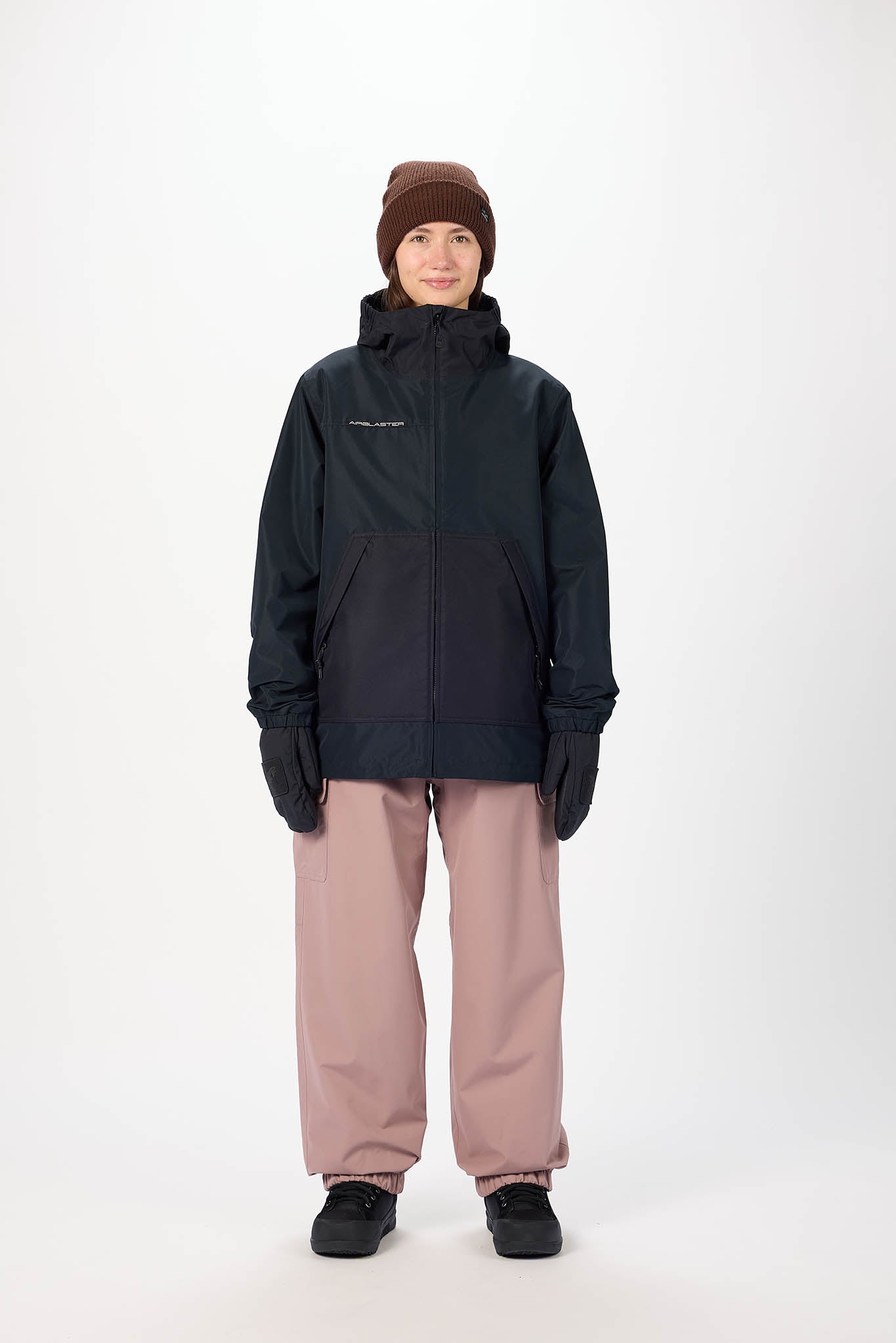 Person wearing a black jacket, pink pants, and a brown beanie on a white background