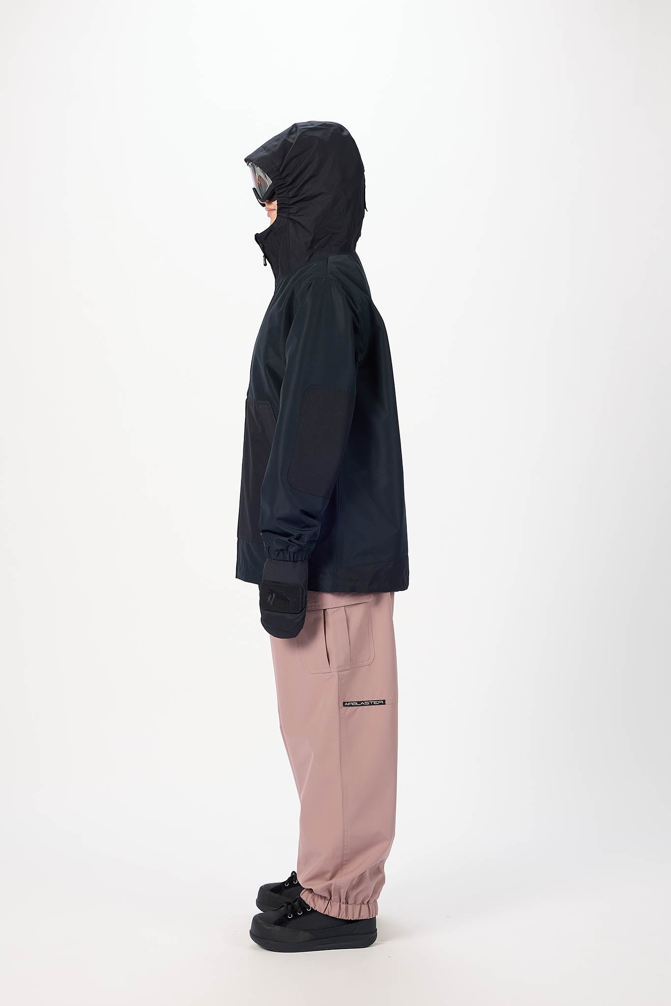 Person wearing a black jacket and pink pants on a white background
