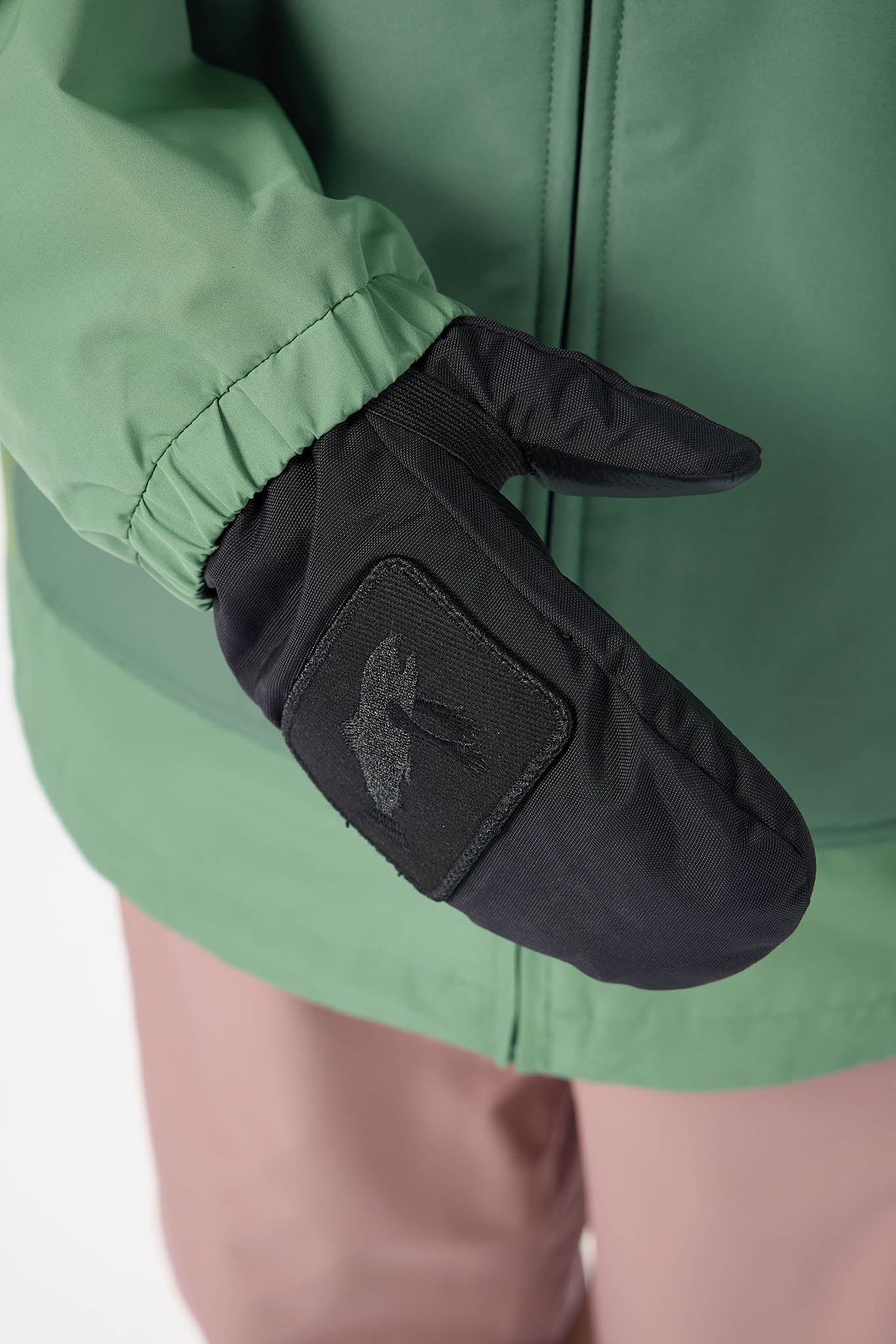Black glove with a logo on a green jacket