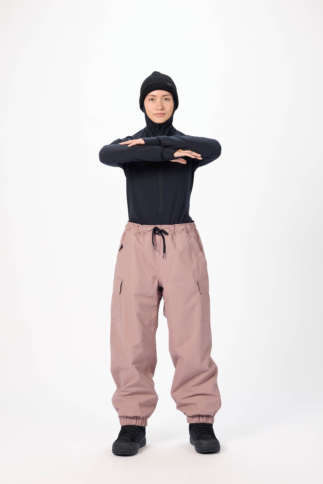 Person wearing a black jacket and pink cargo pants on a white background