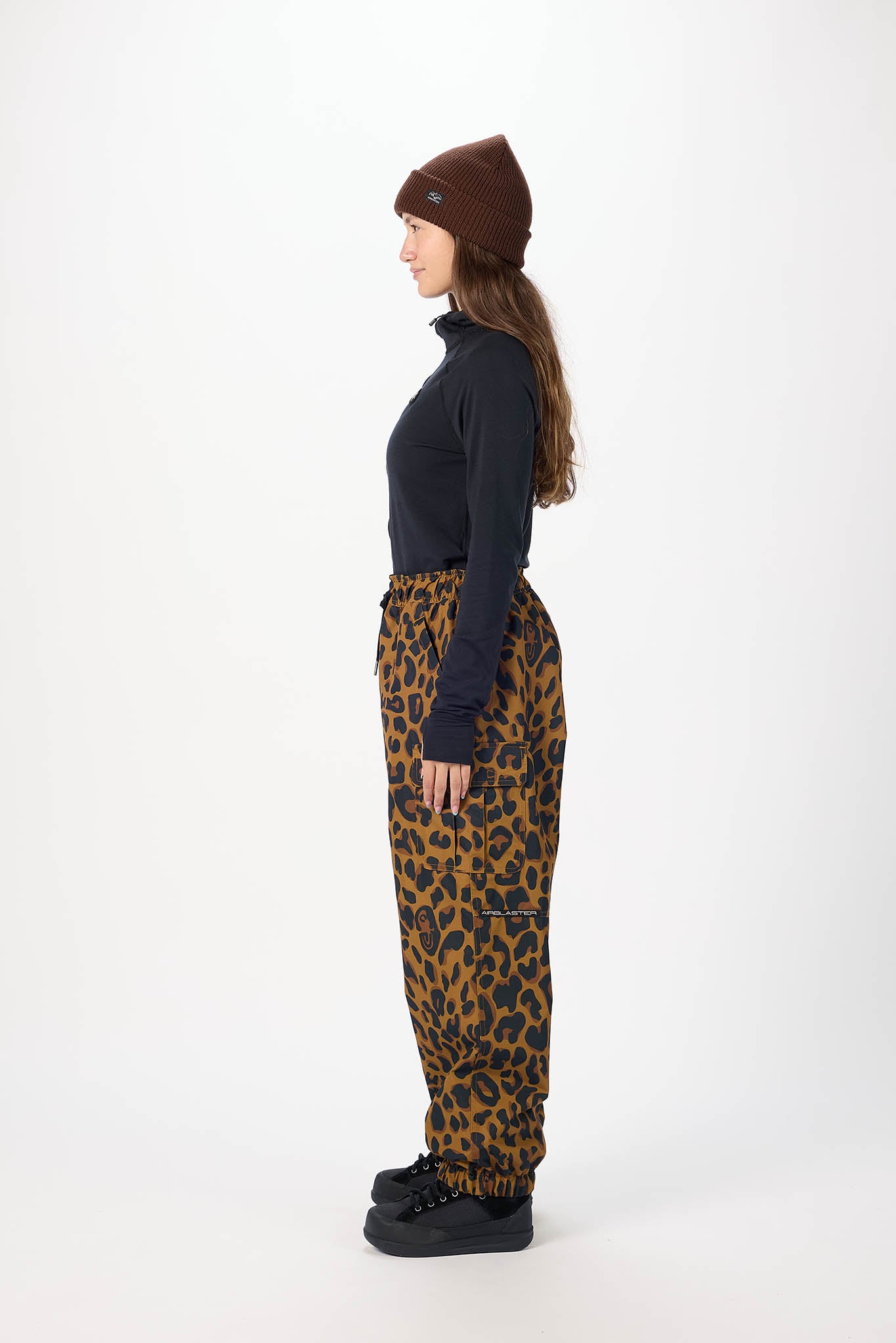 Person wearing a black top, brown beanie, and leopard print pants on a white background