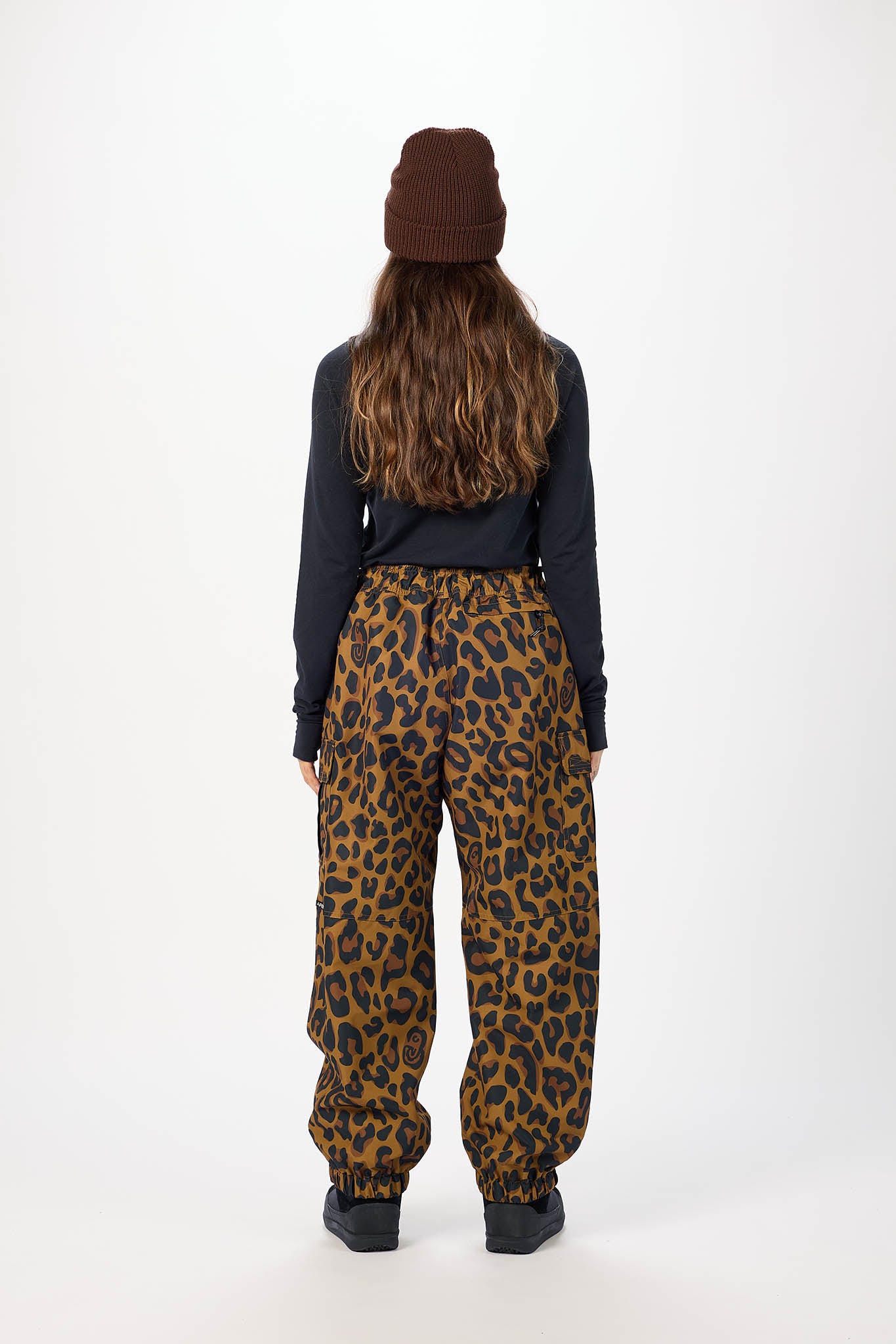 Person wearing a dark jacket and leopard print pants on a white background