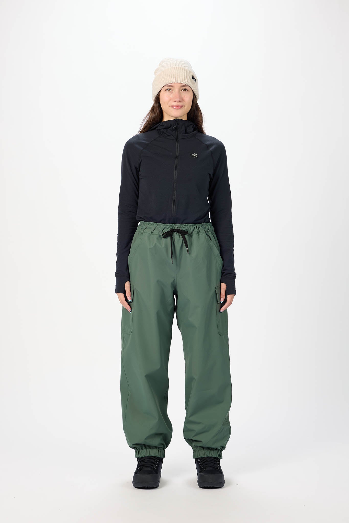 Person wearing a black hoodie and green pants on a white background