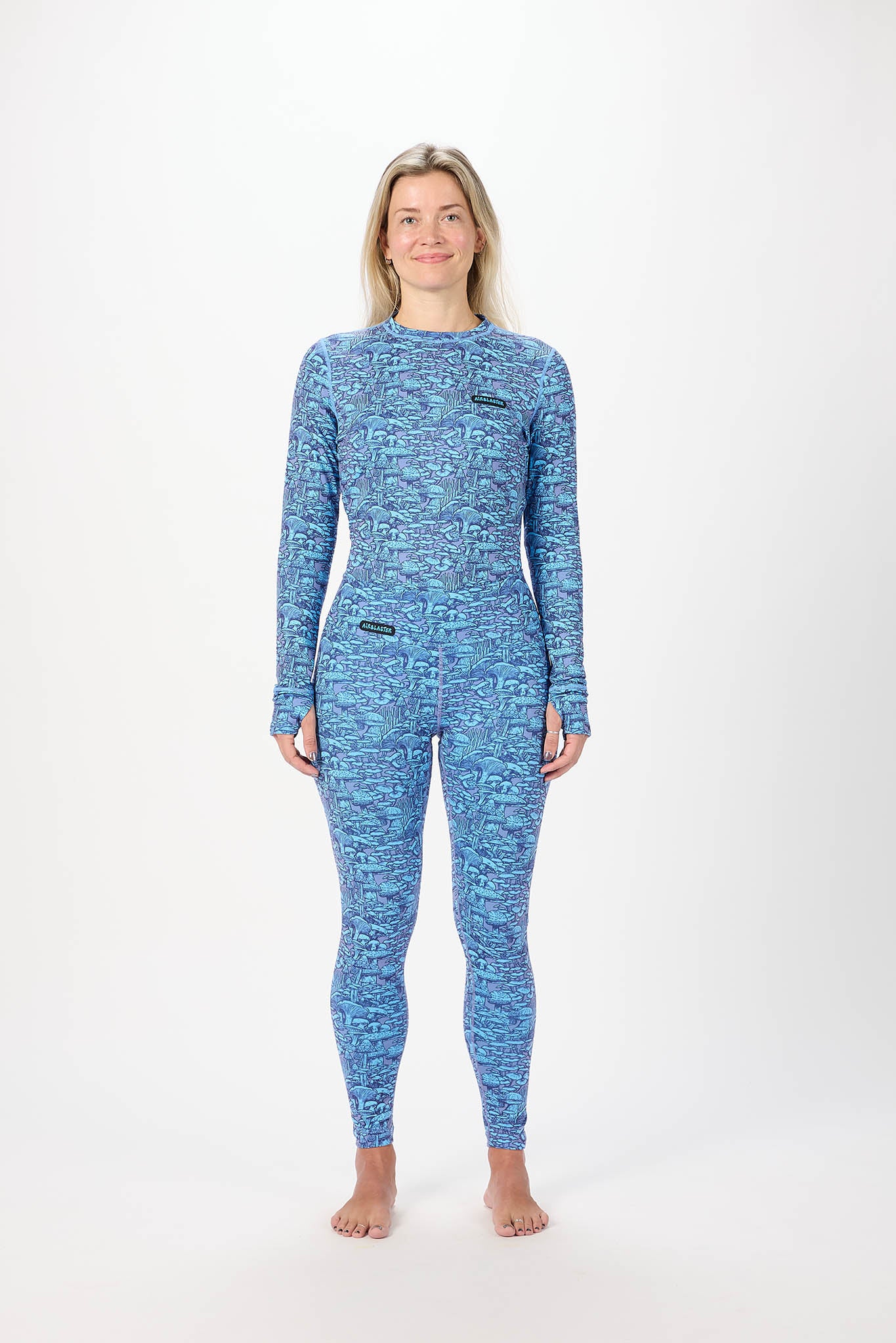 A woman modeling a matching set of mushroom pattern base layers  a blue and against a plain white studio background.