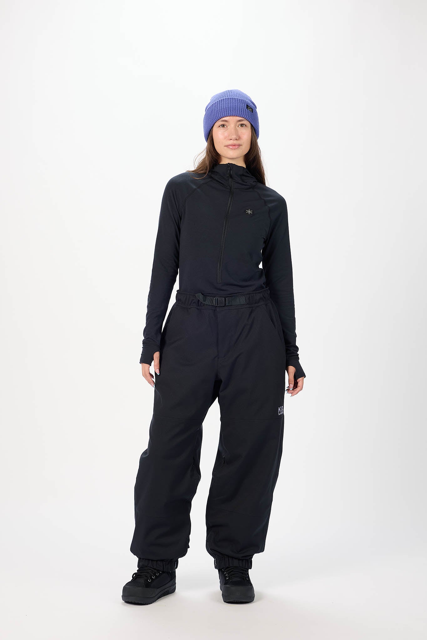 Person wearing a black snowsuit with a blue beanie on a white background