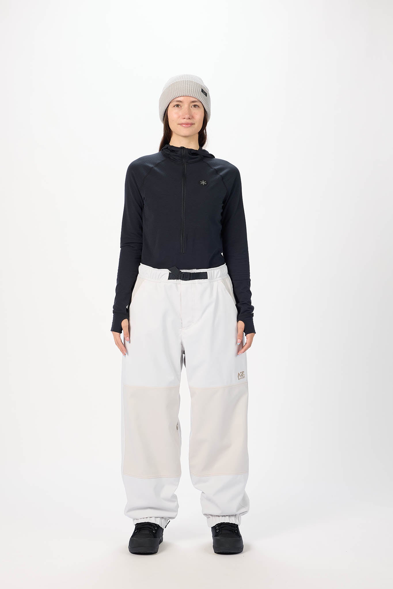 Person wearing a black long-sleeve top and white pants on a white background