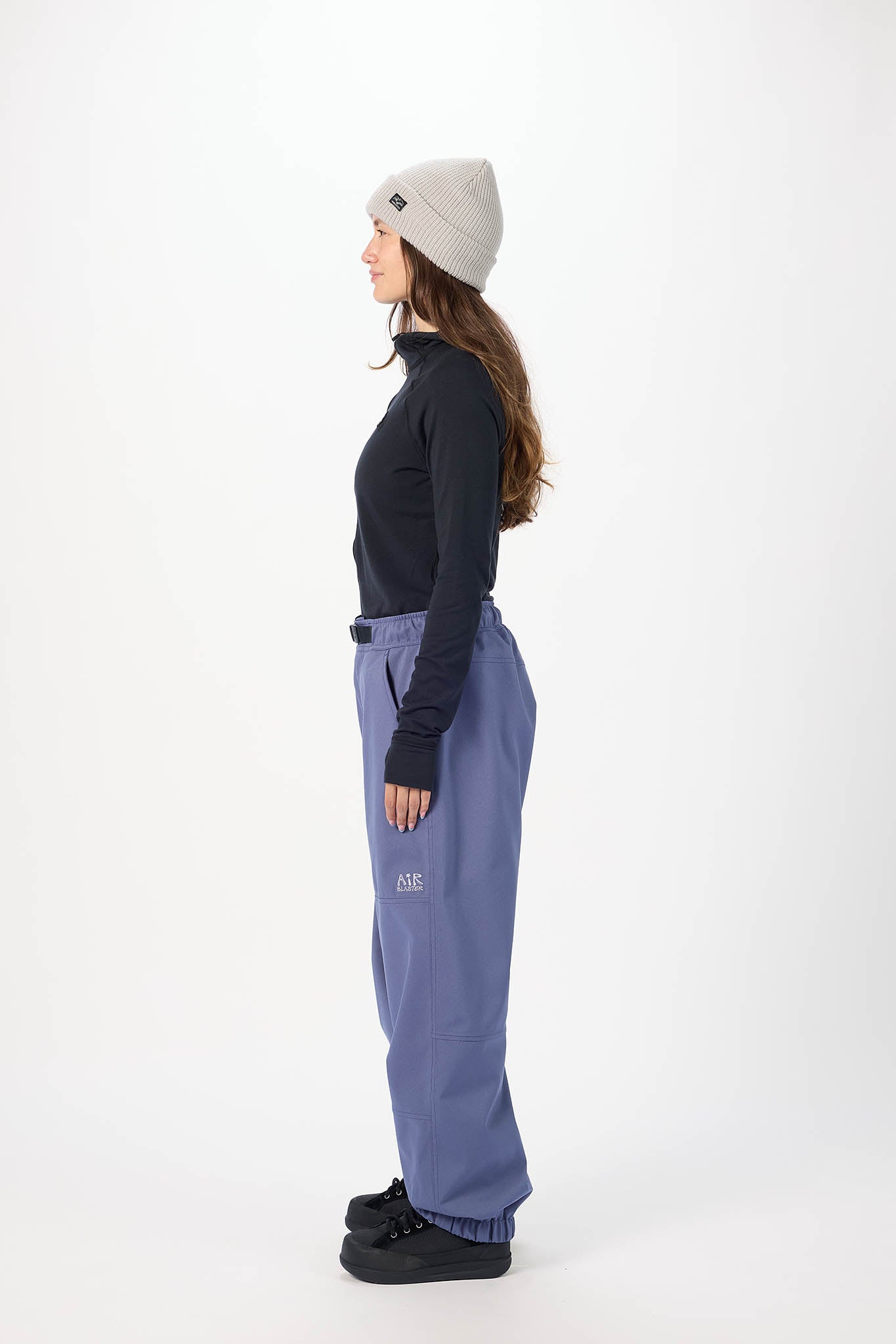 Person wearing a black jacket, blue pants, and a gray beanie on a white background