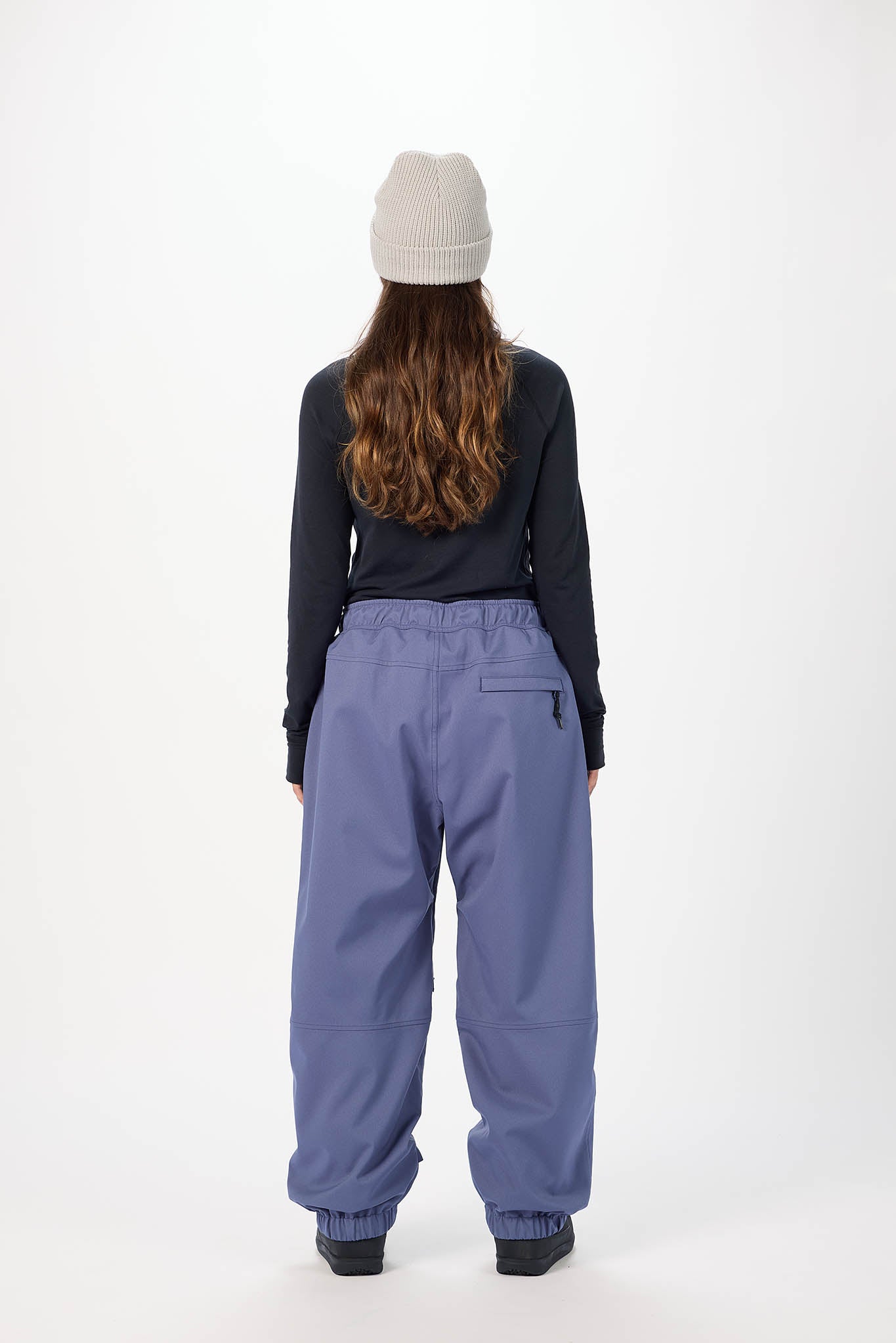 Person wearing a black jacket and blue pants with a white background