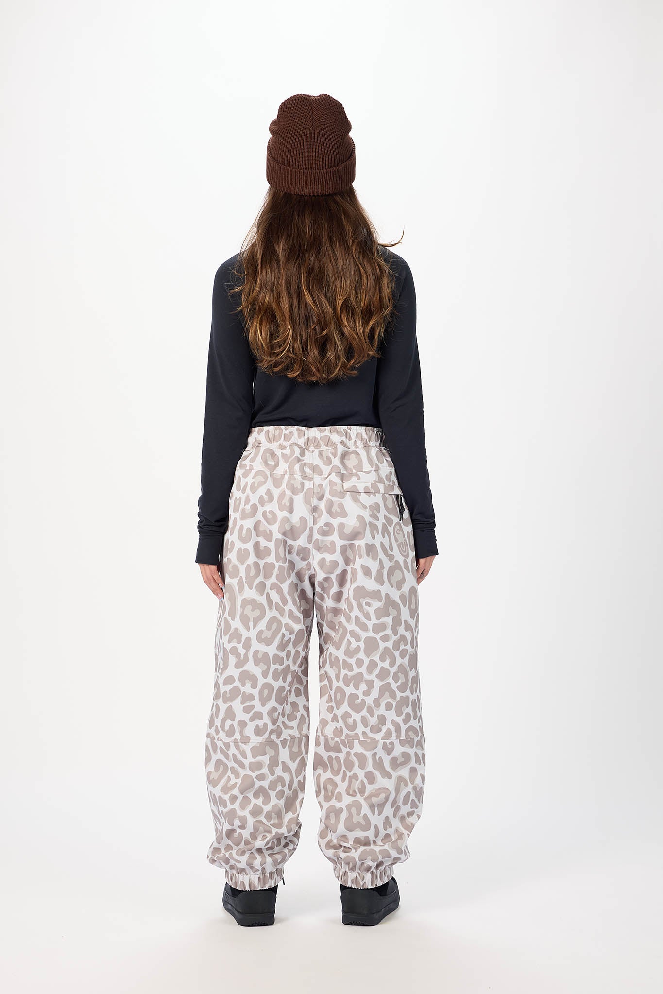 Person wearing leopard print pants and a dark long-sleeve shirt on a white background