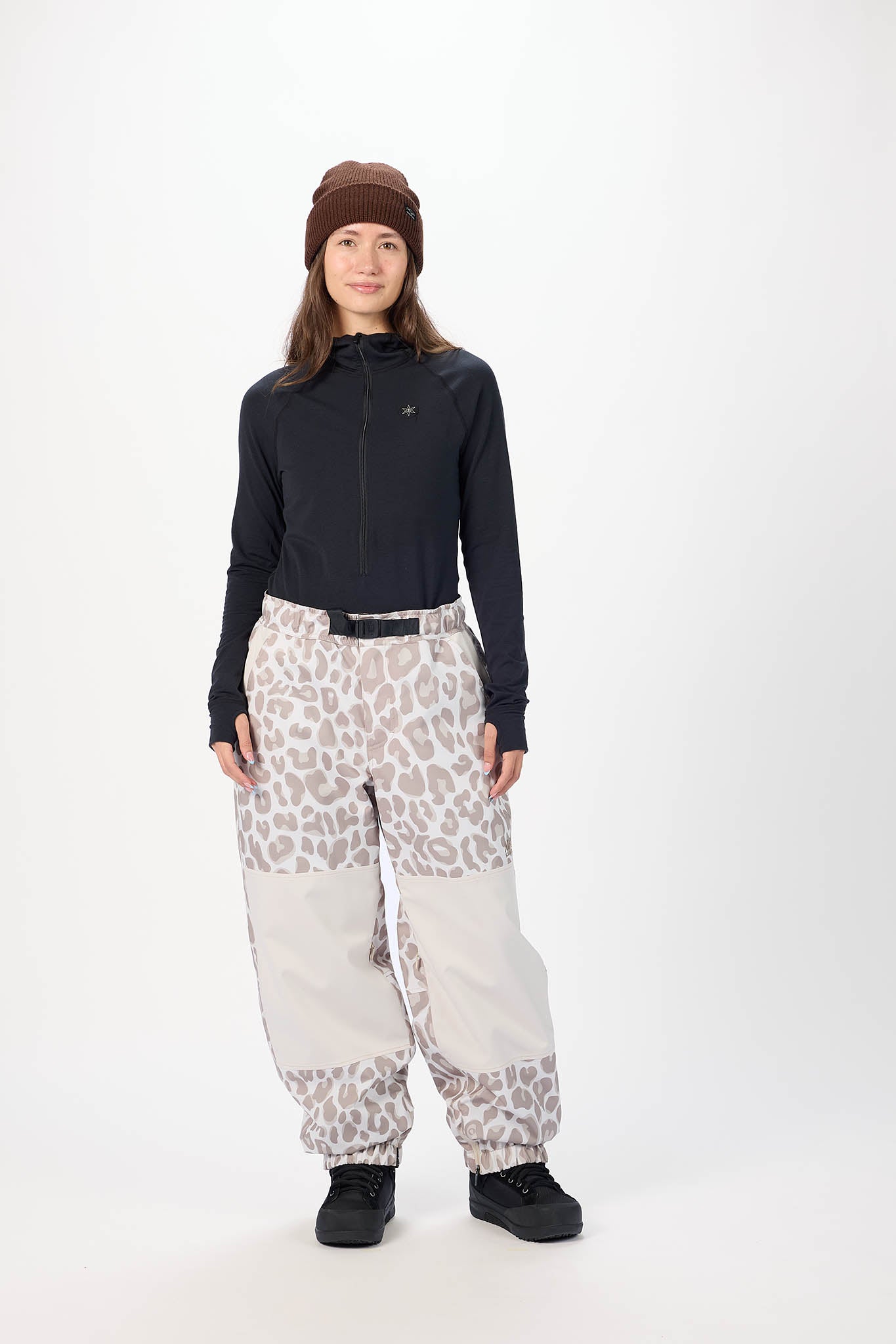 Person wearing a black long-sleeve top and white pants with a leopard print pattern on a white background