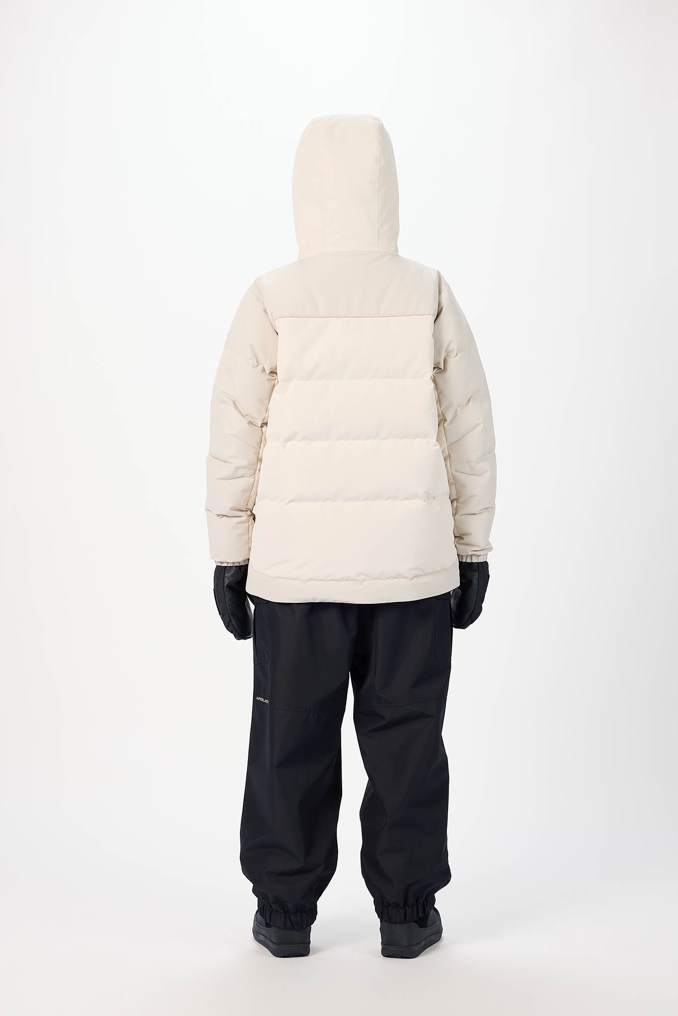 Person wearing a beige puffer jacket and black pants on a white background