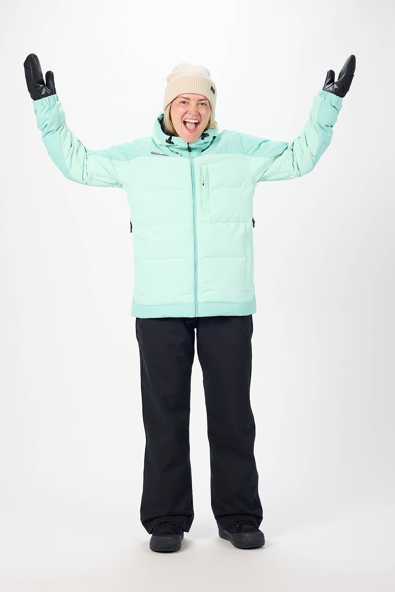 Person wearing a light blue snow jacket and black pants on a white background