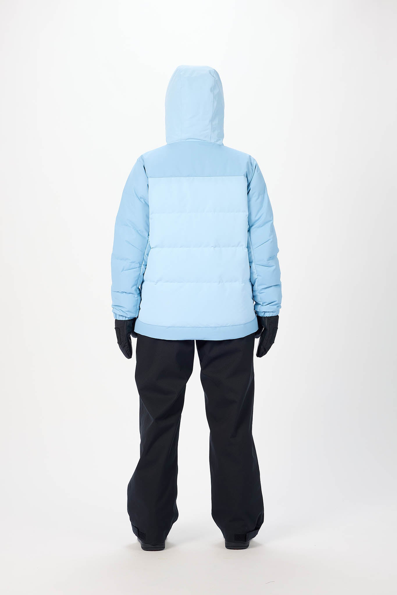 Person wearing a light blue puffer jacket and black pants on a white background