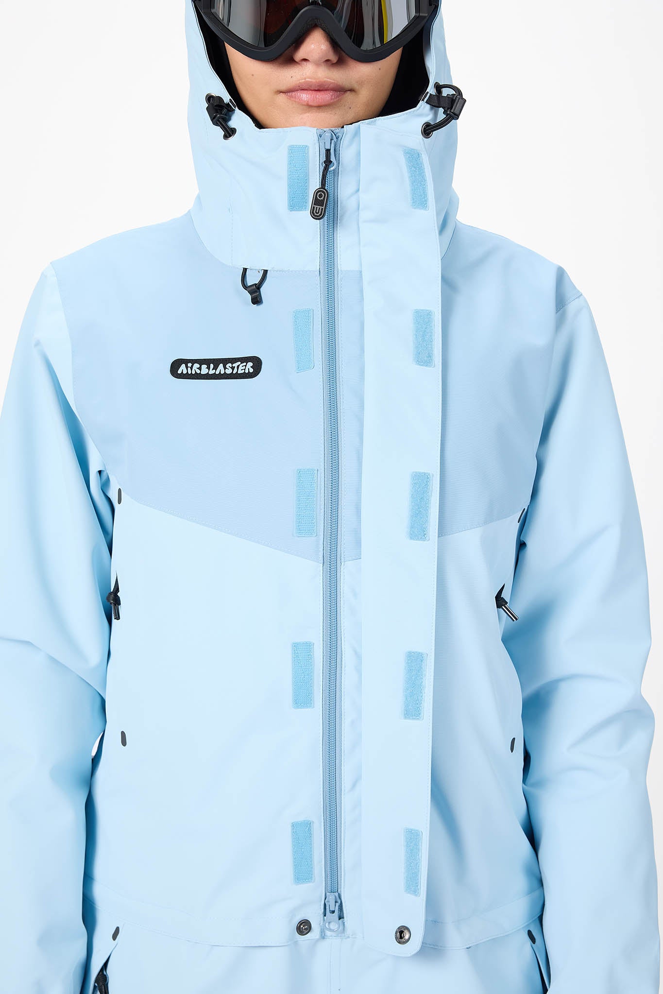 close up person wearing a light blue  snowsuit on a white background