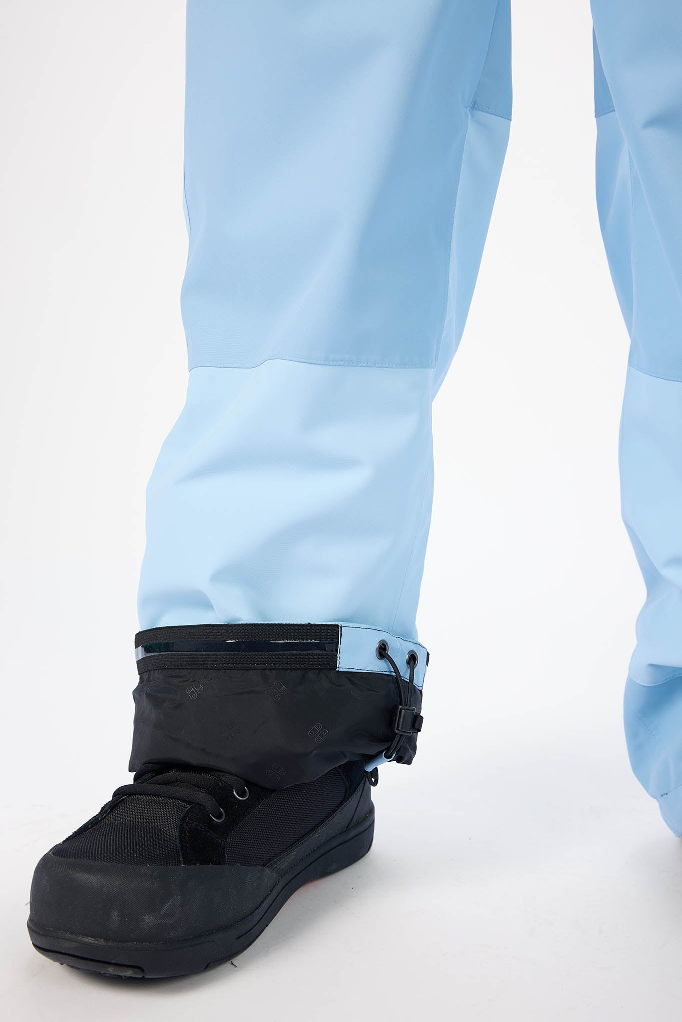 Black snow boots with blue pants on a white background