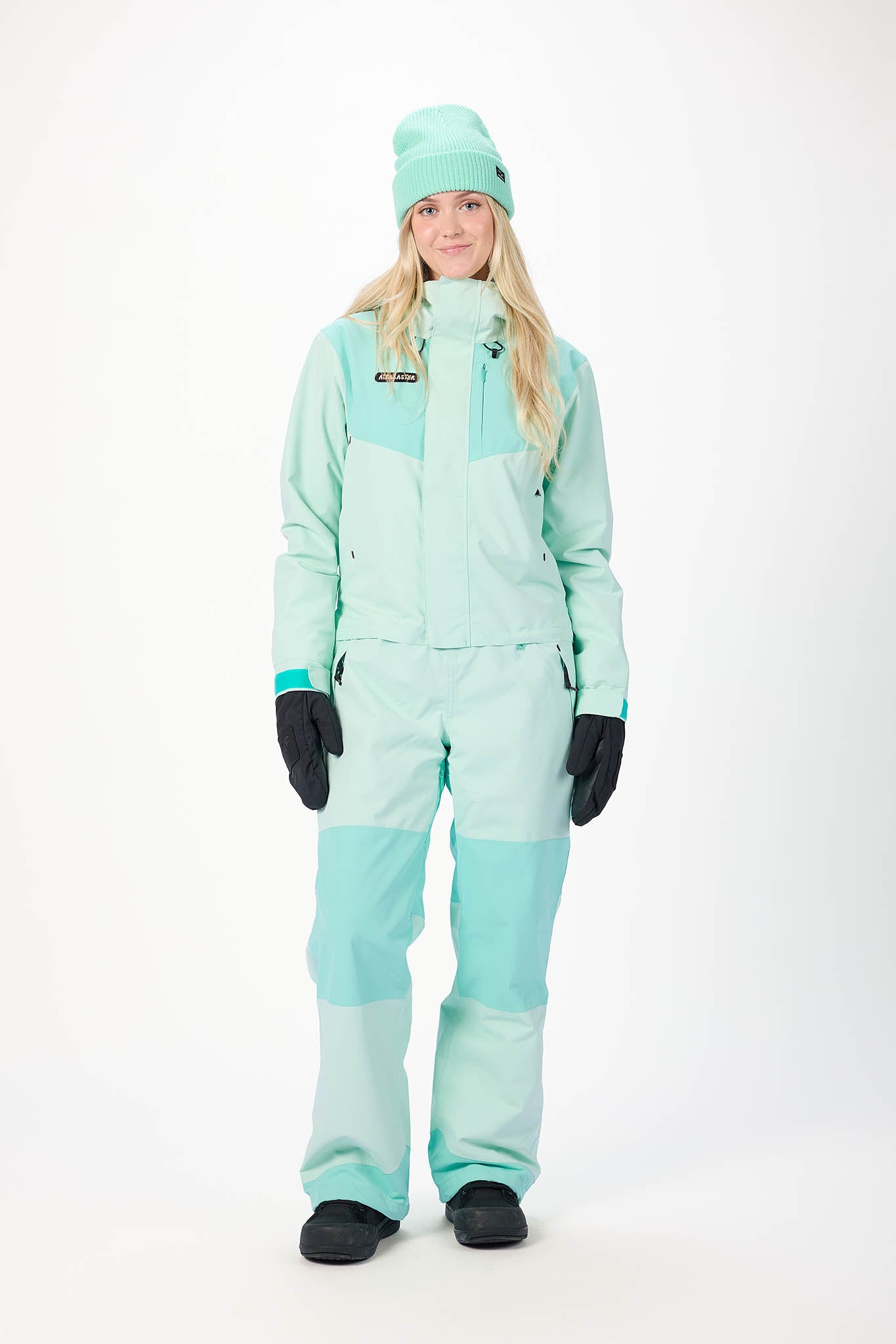 Person wearing a mint snowsuit on a white background