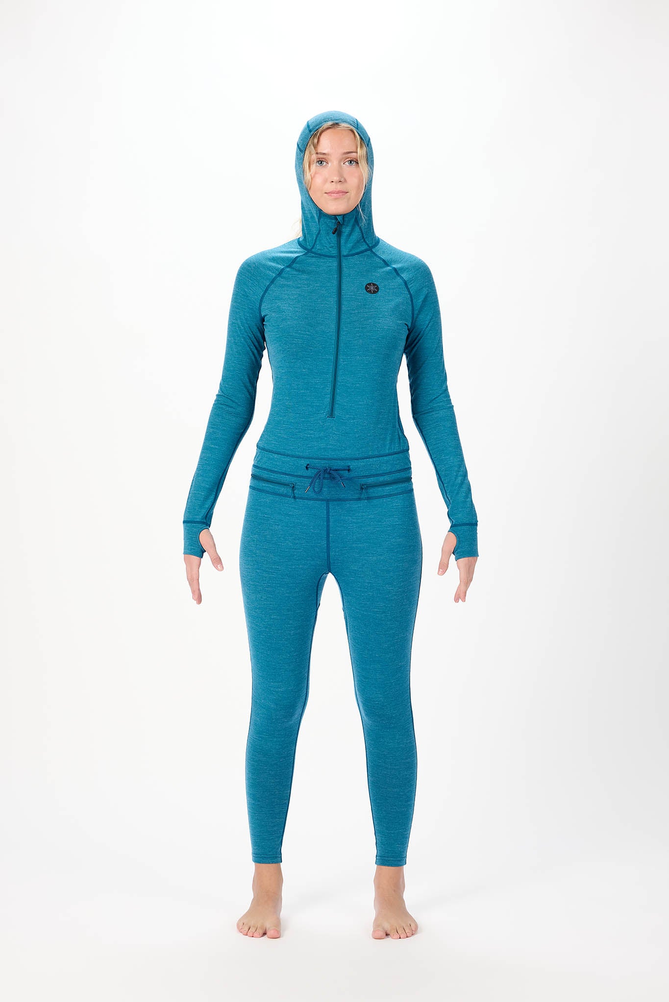 A woman modeling a teal full-body hooded wetsuit against a plain white studio background.