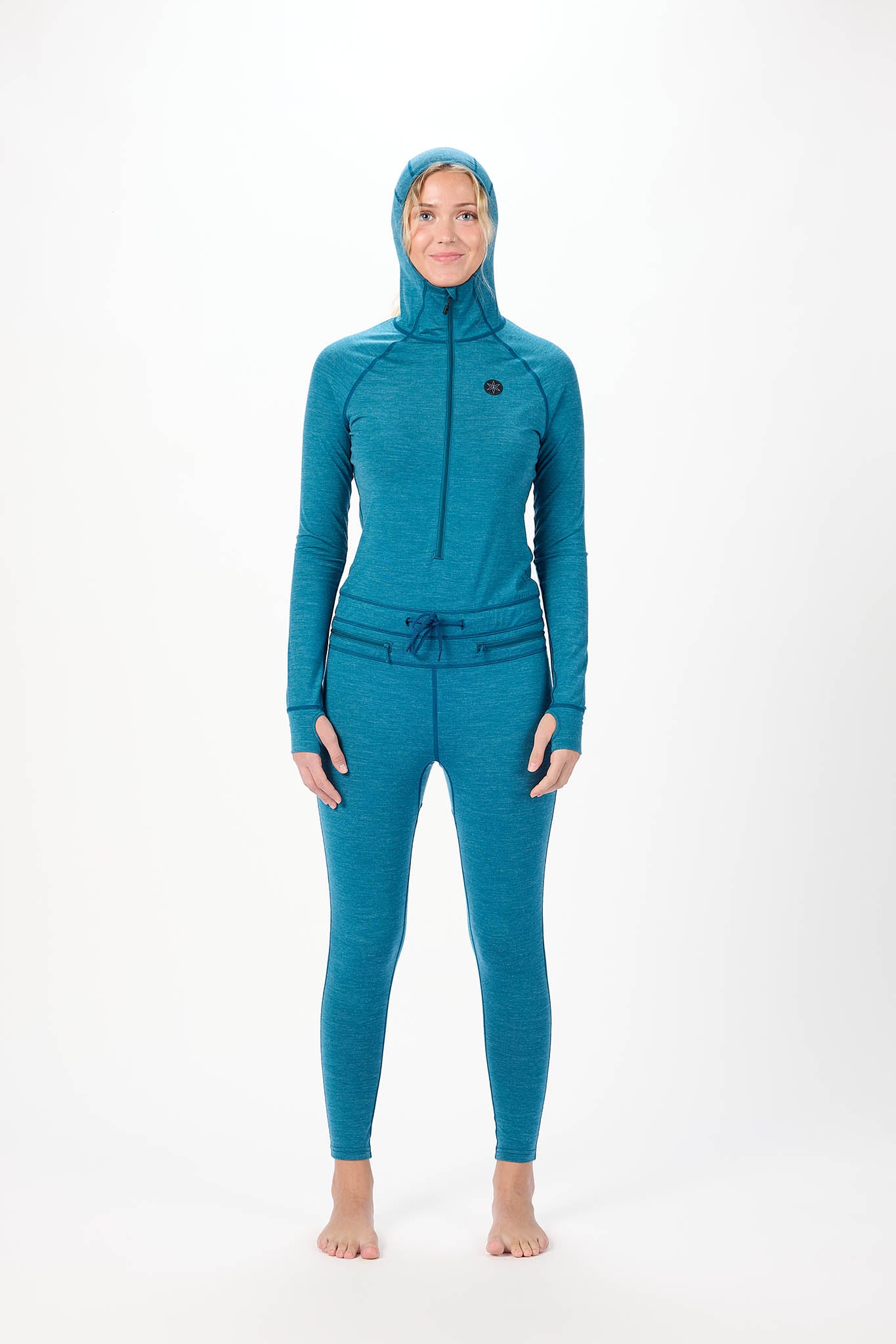 A woman modeling a teal full-body hooded wetsuit or swimwear set against a plain white studio background. The set includes a long-sleeve zip-front hooded top and matching fitted leggings.