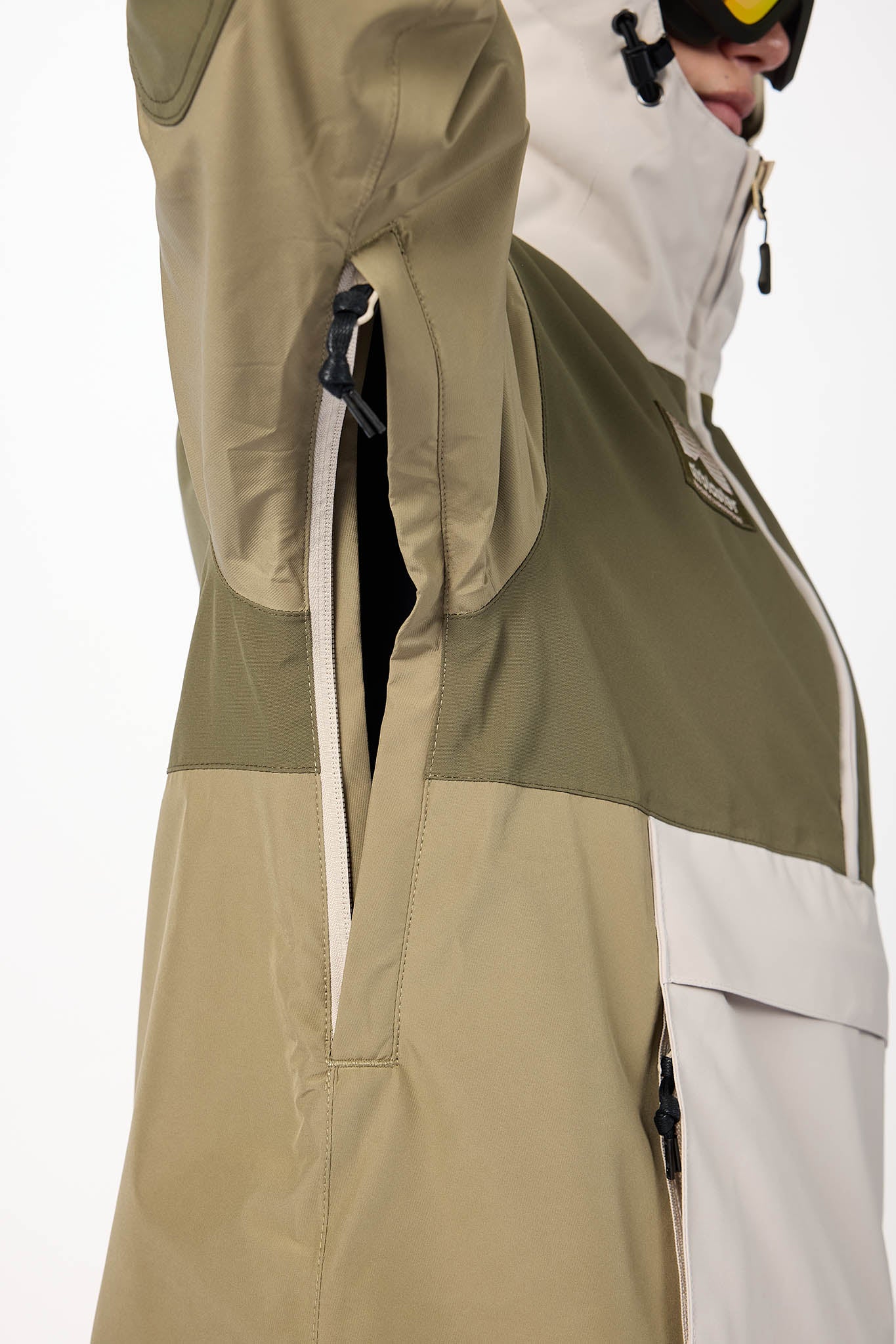 Person wearing a green and beige snowboard jacket on a white background