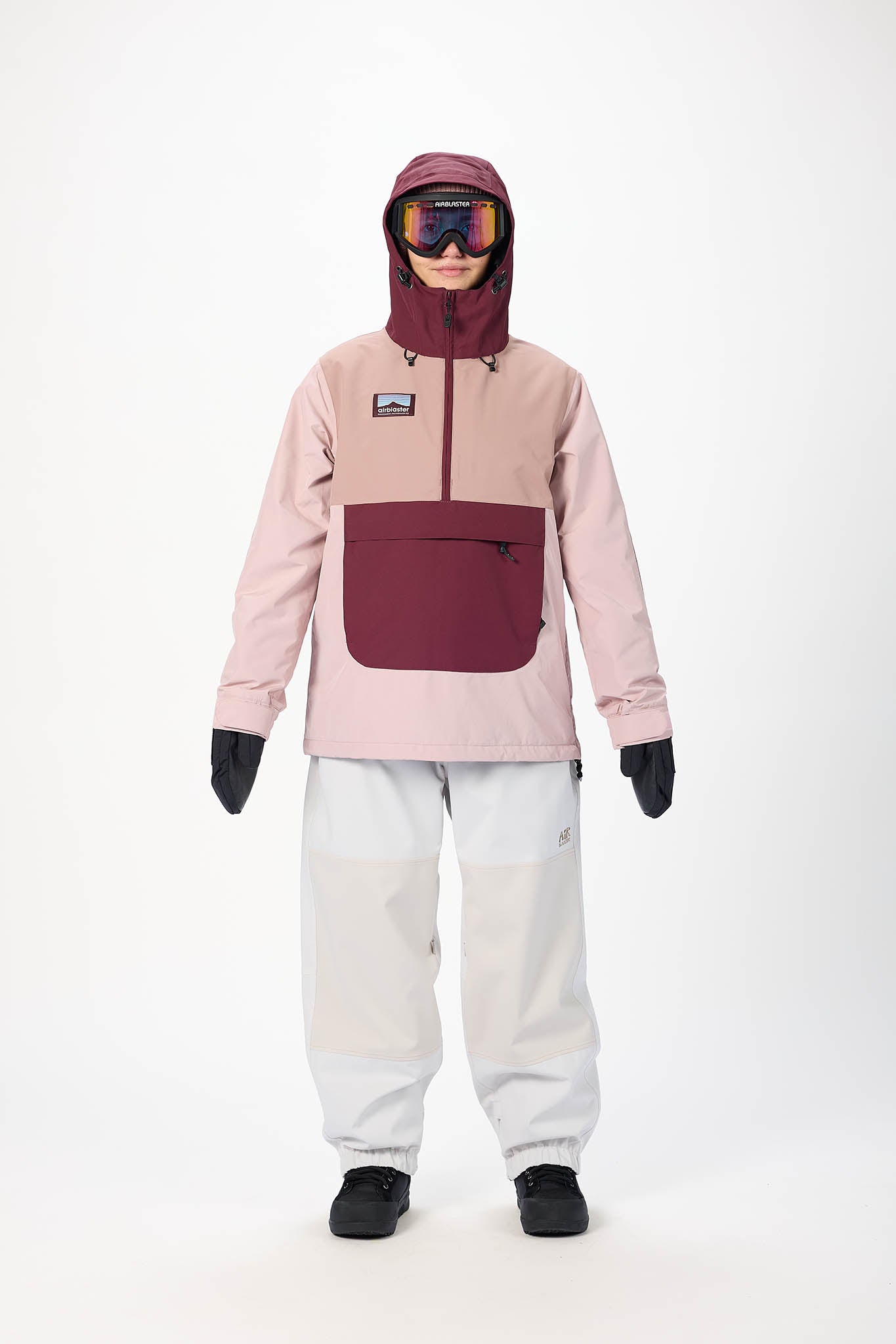 Person wearing a pink and maroon snow jacket with a hood, white pants, and black gloves on a white background.