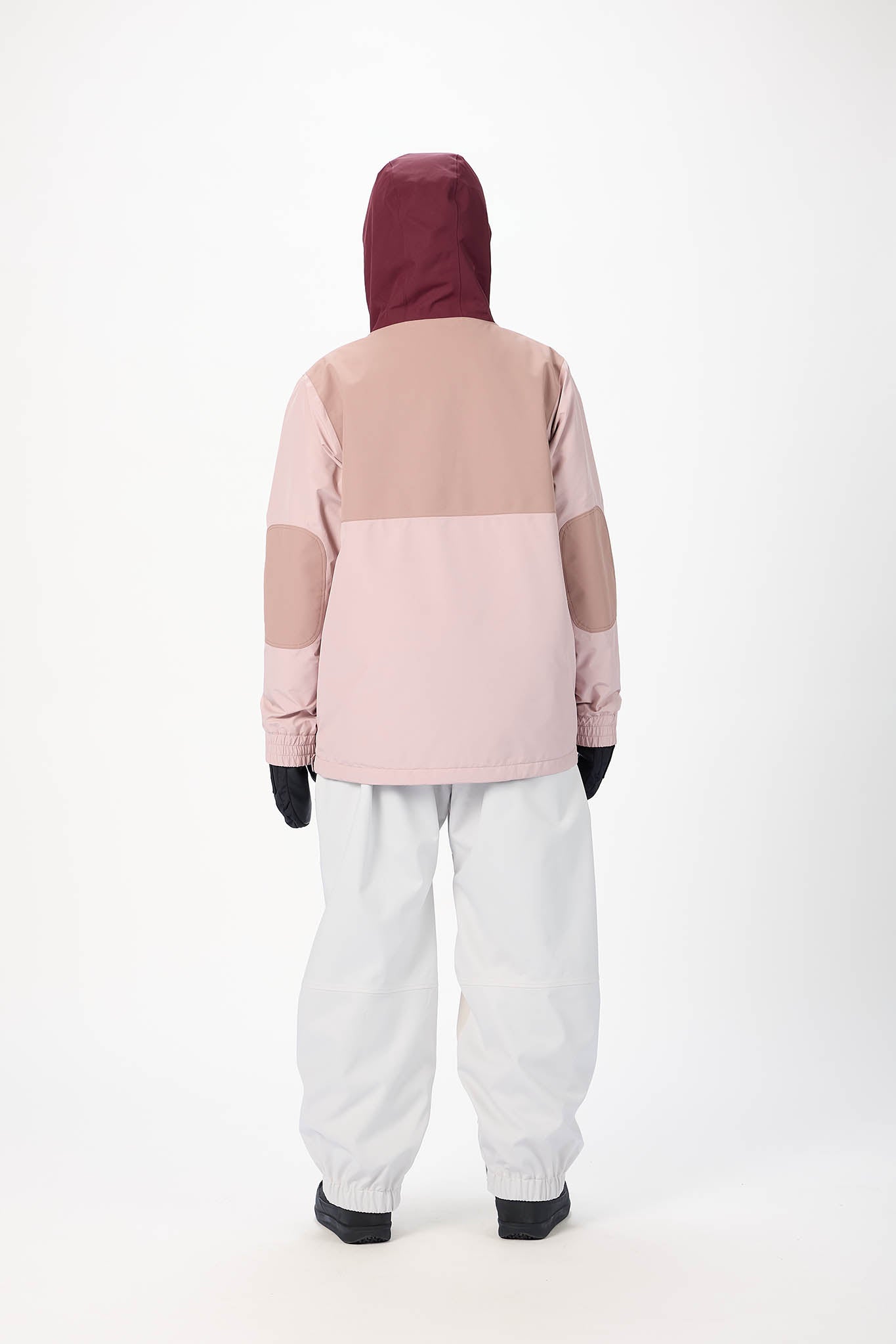 Person wearing a two-tone pink and beige jacket with a hood on a white background