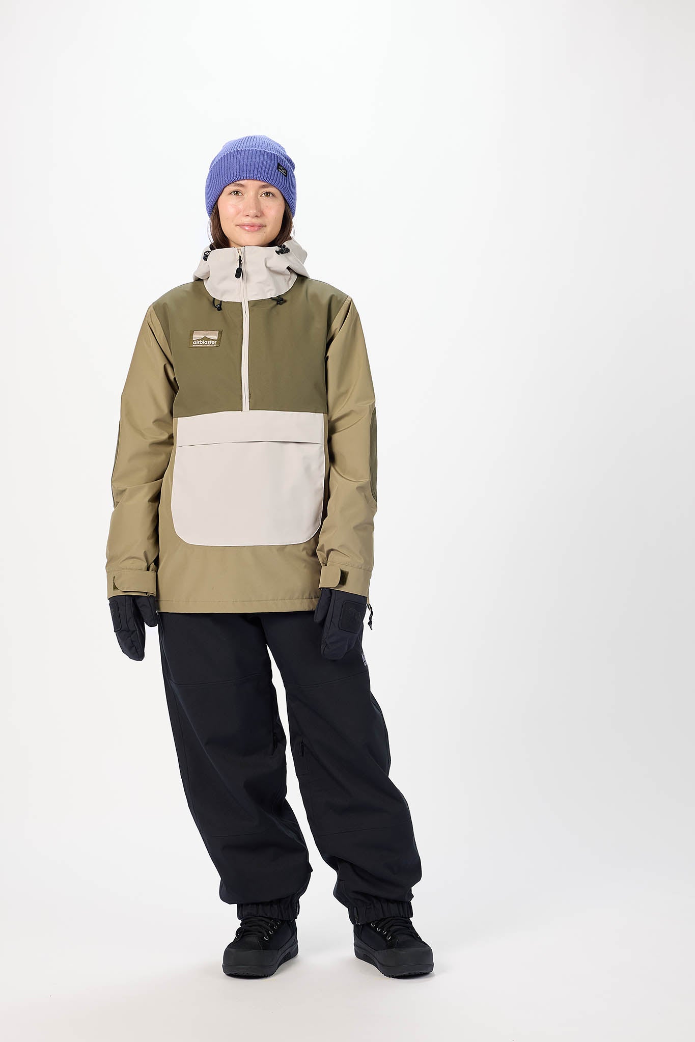 Person wearing a green and beige snowboard jacket with black pants on a white background