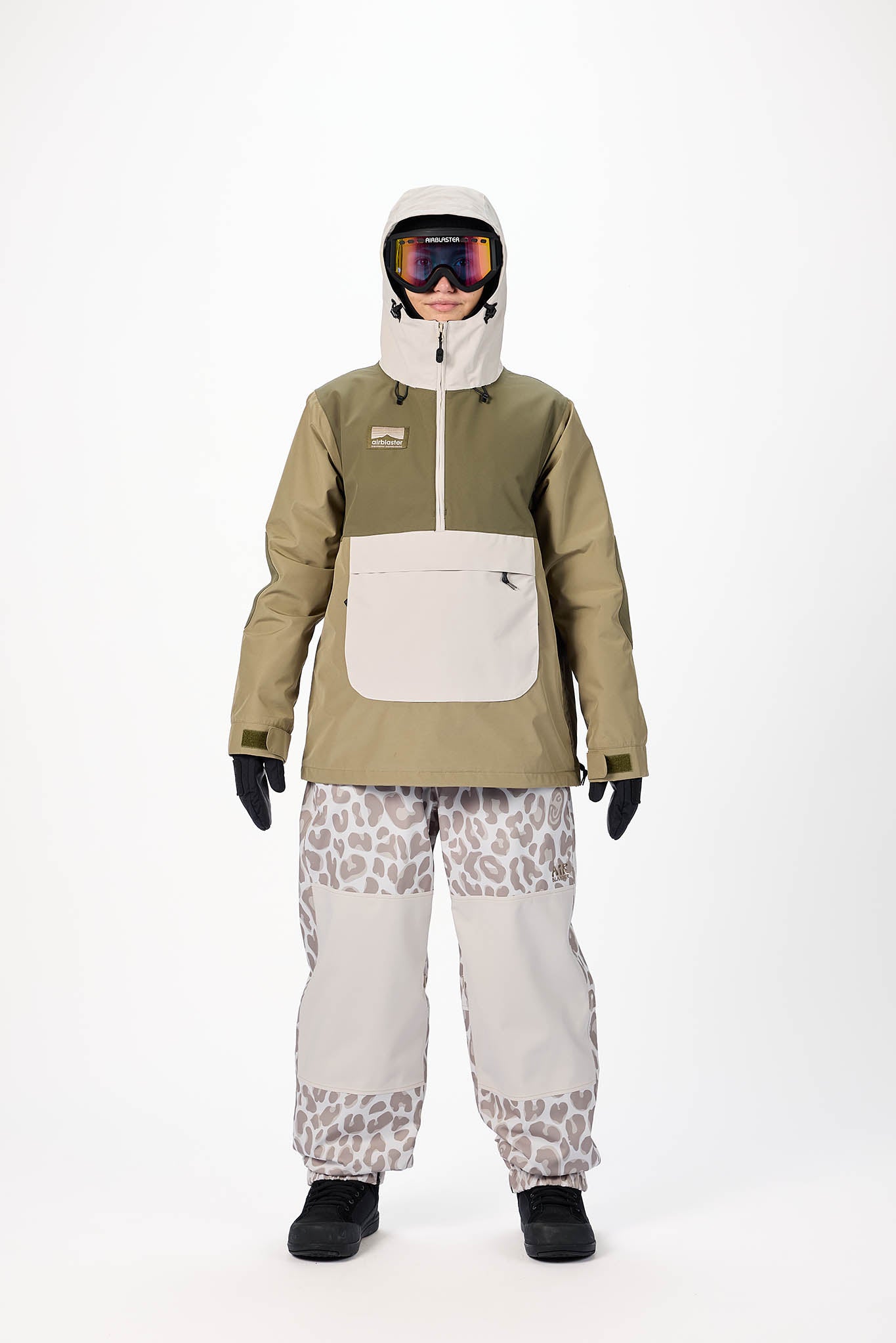 Person wearing a green snow jacket and patterned pants on a white background