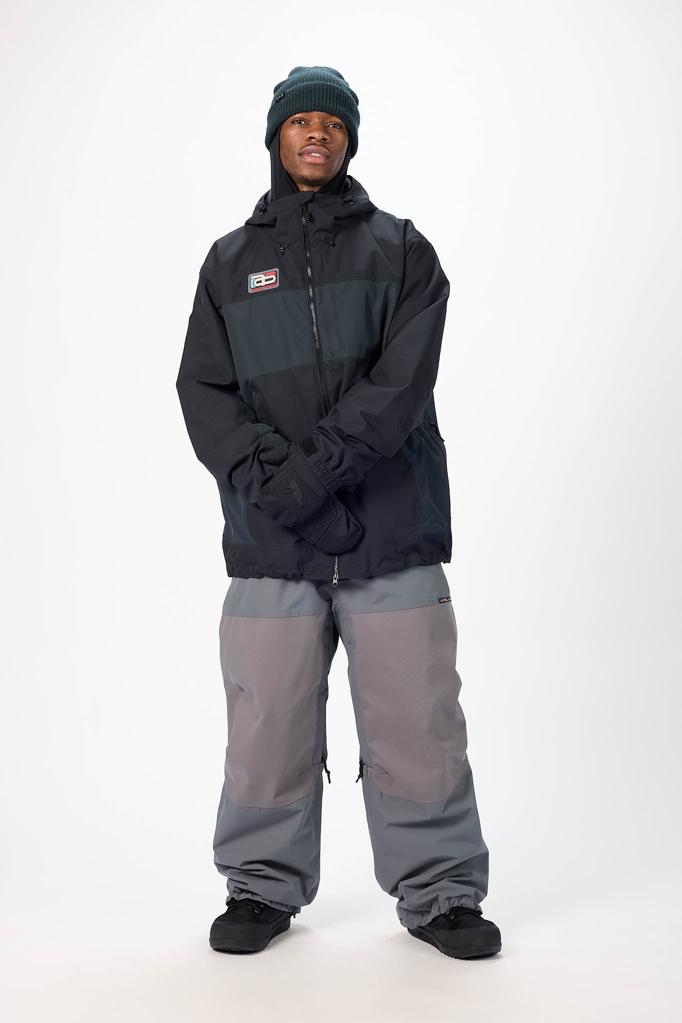 Person wearing a black jacket and gray pants on a white background