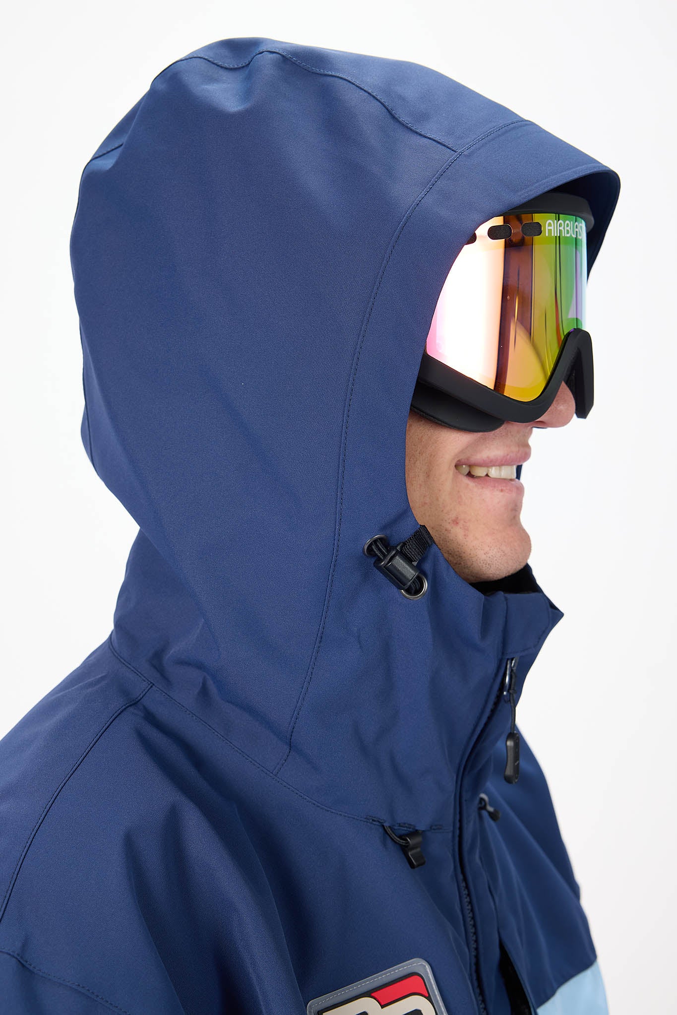 Person wearing a blue hooded jacket with reflective goggles on a white background