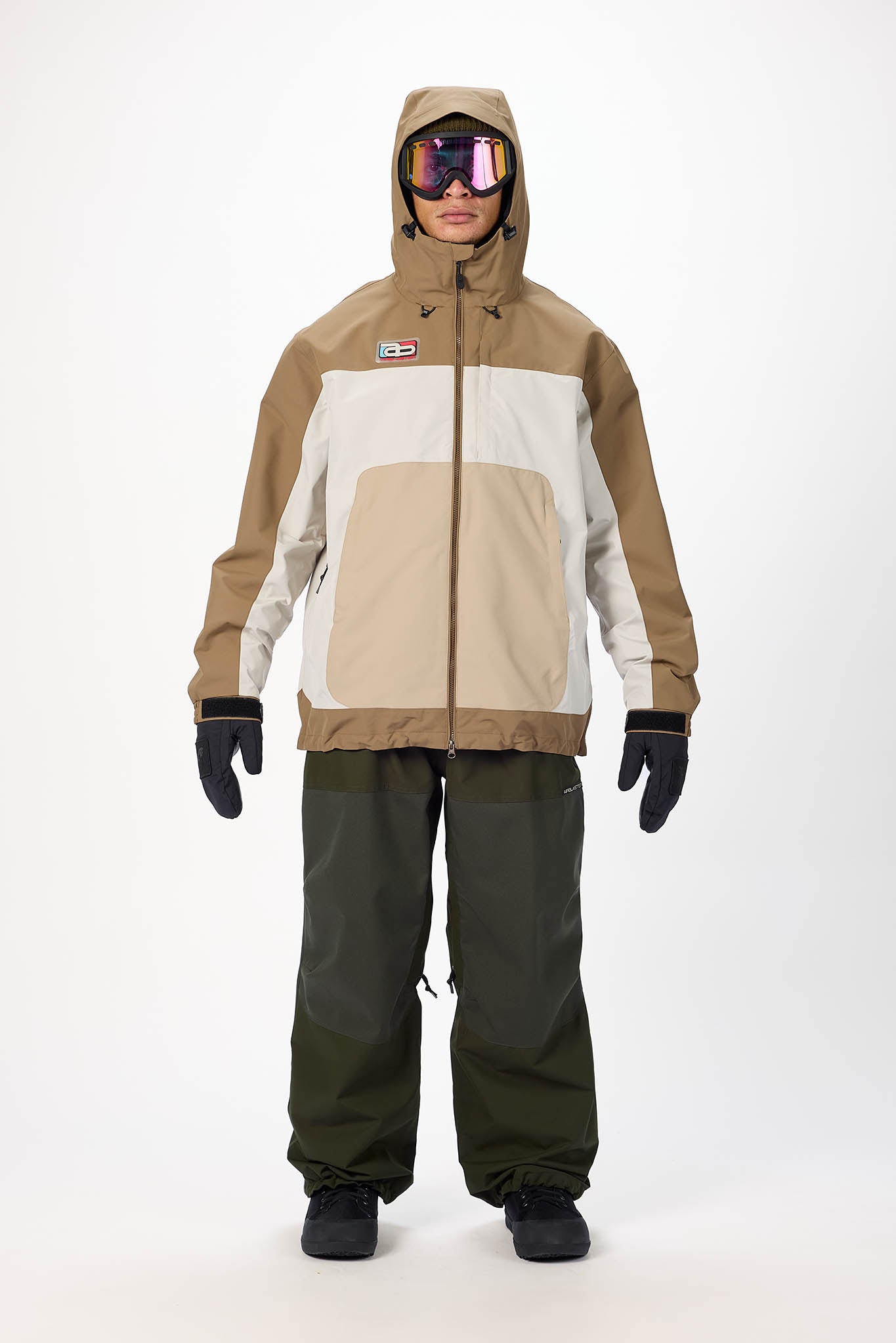 Person wearing a brown and beige snowboarding jacket and pants on a white background