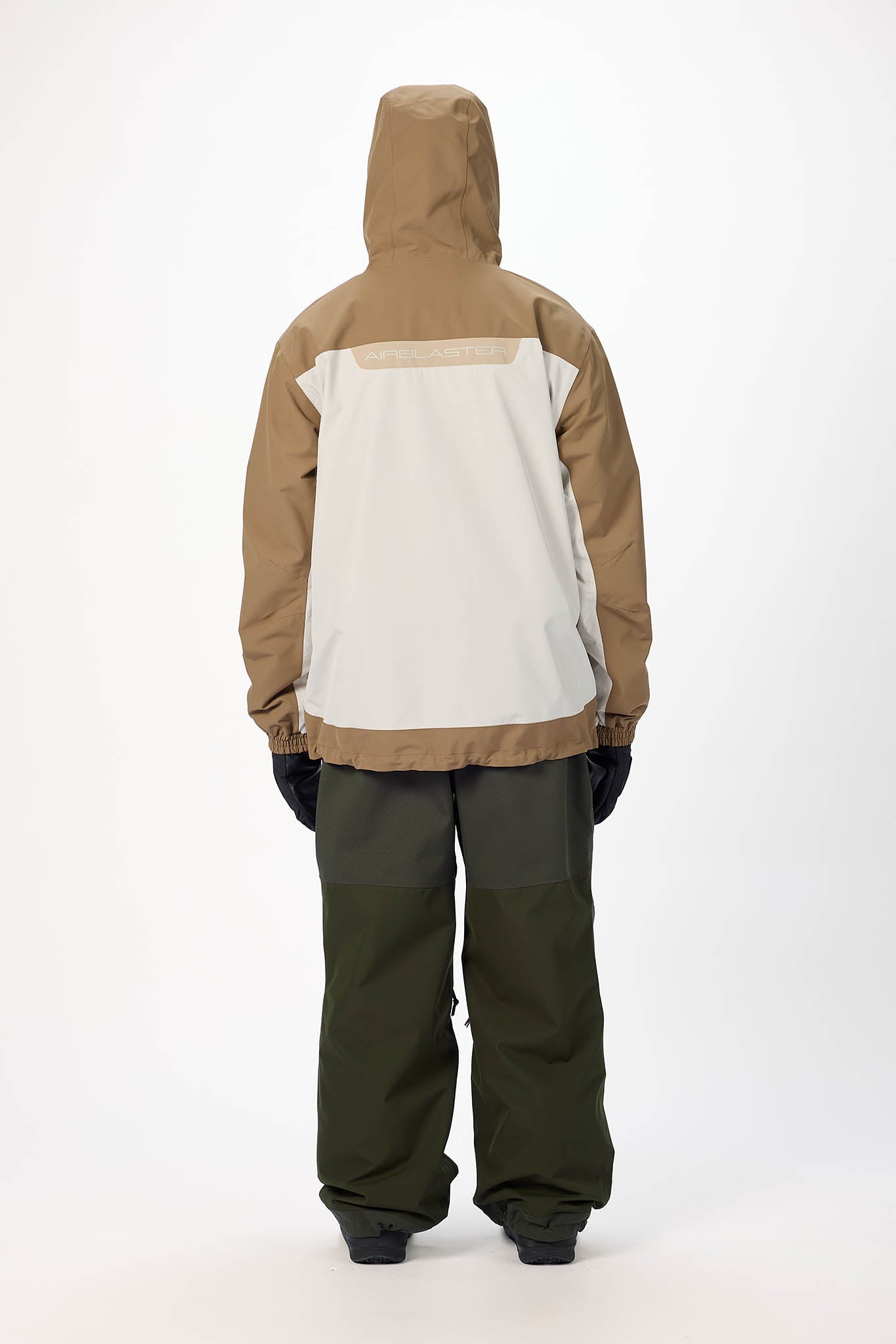 Person wearing a brown and beige jacket with green pants on a white background