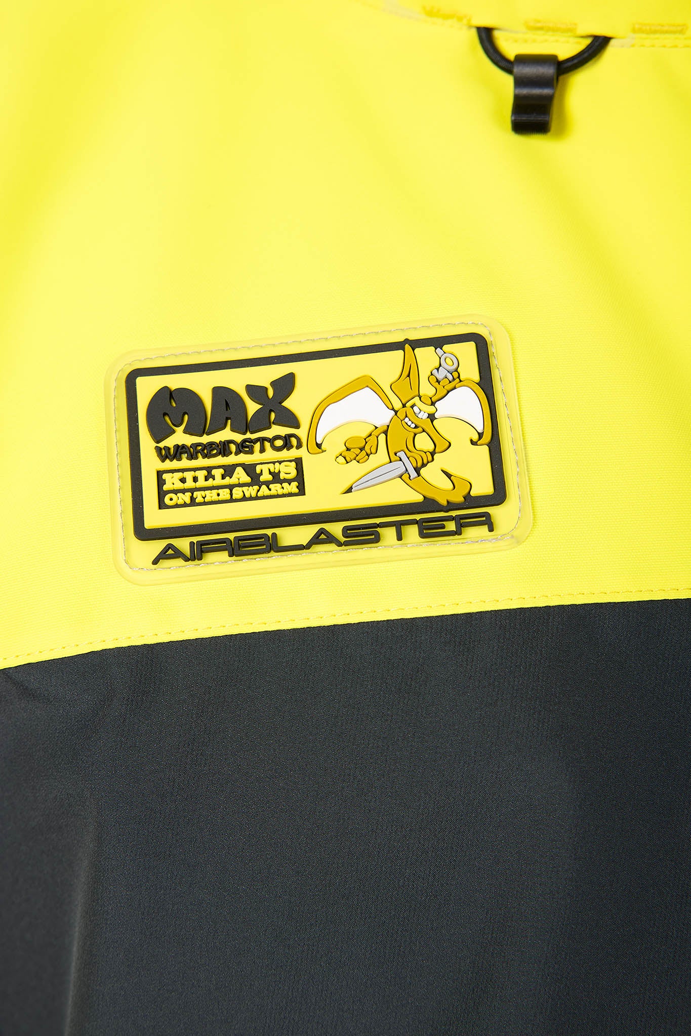 Close-up of a yellow and black jacket with a brand patch featuring a cartoon character and text.