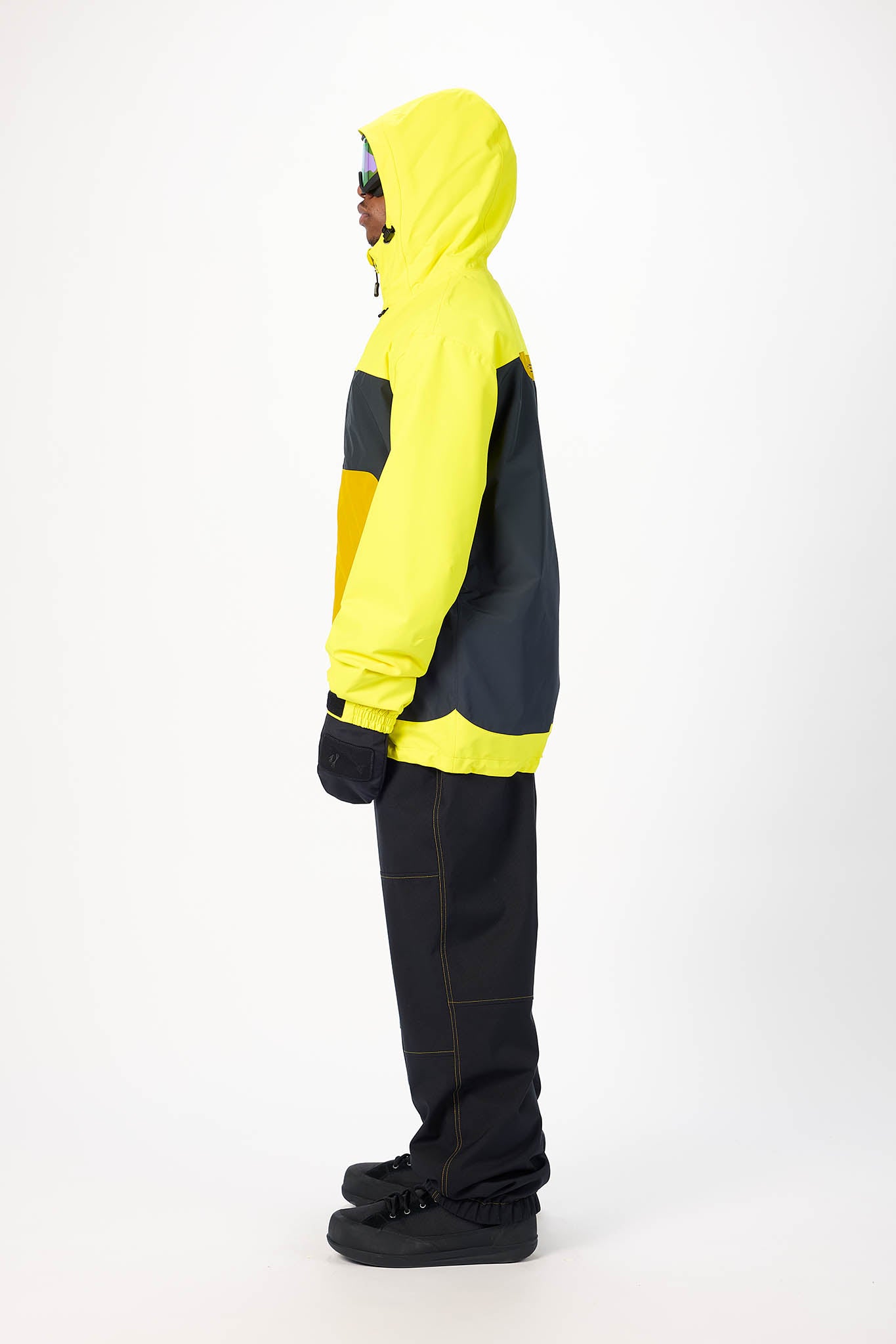 Person wearing a yellow and black jacket with black pants on a white background