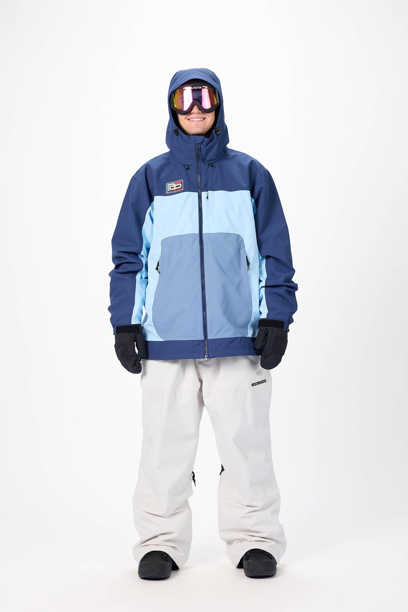 Person wearing a blue and light blue snow jacket with white pants on a white background