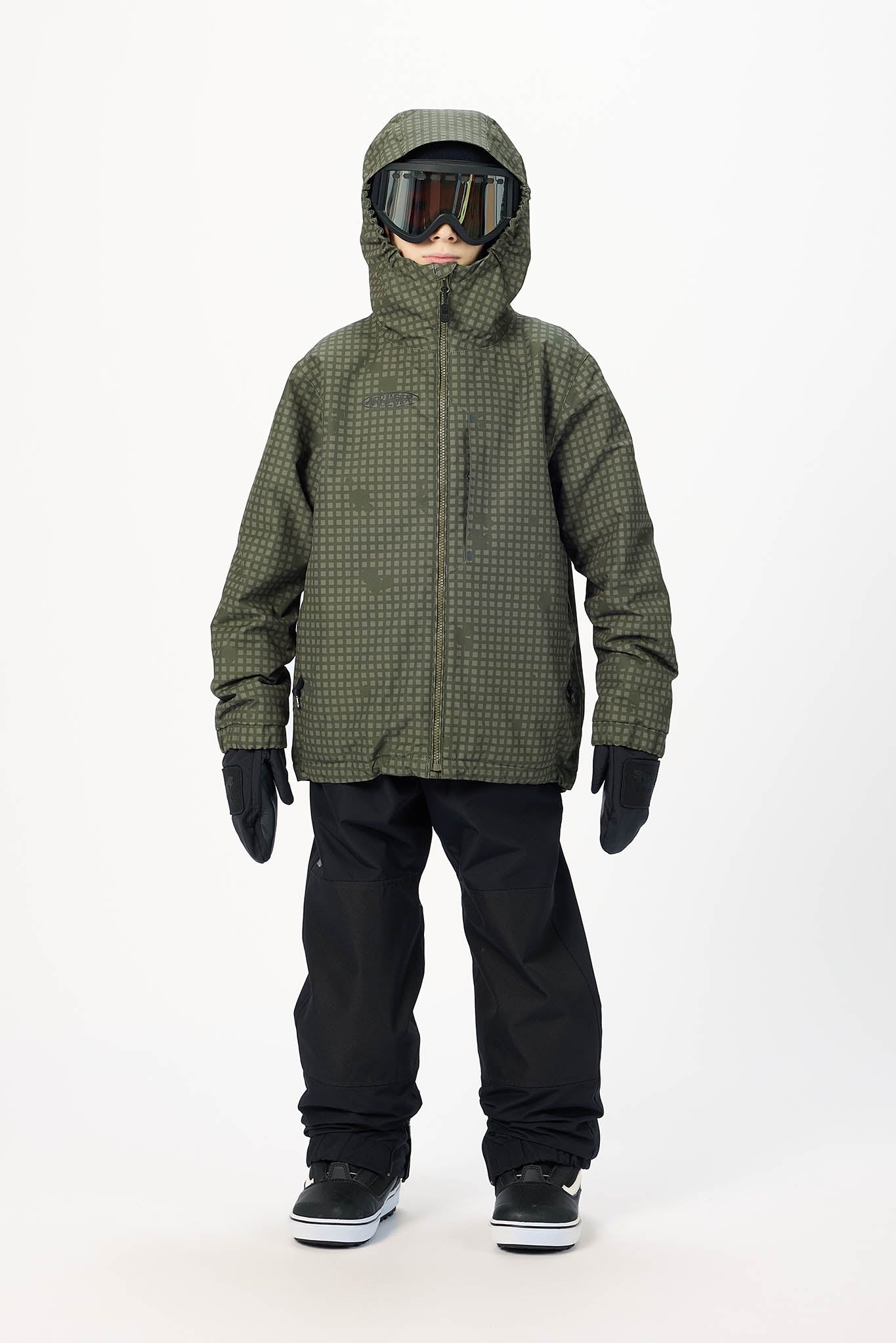 A child modeling an olive green hooded snowboard jacket with a subtle grid pattern, black snow pants, black gloves, and goggles, standing against a plain white studio background.