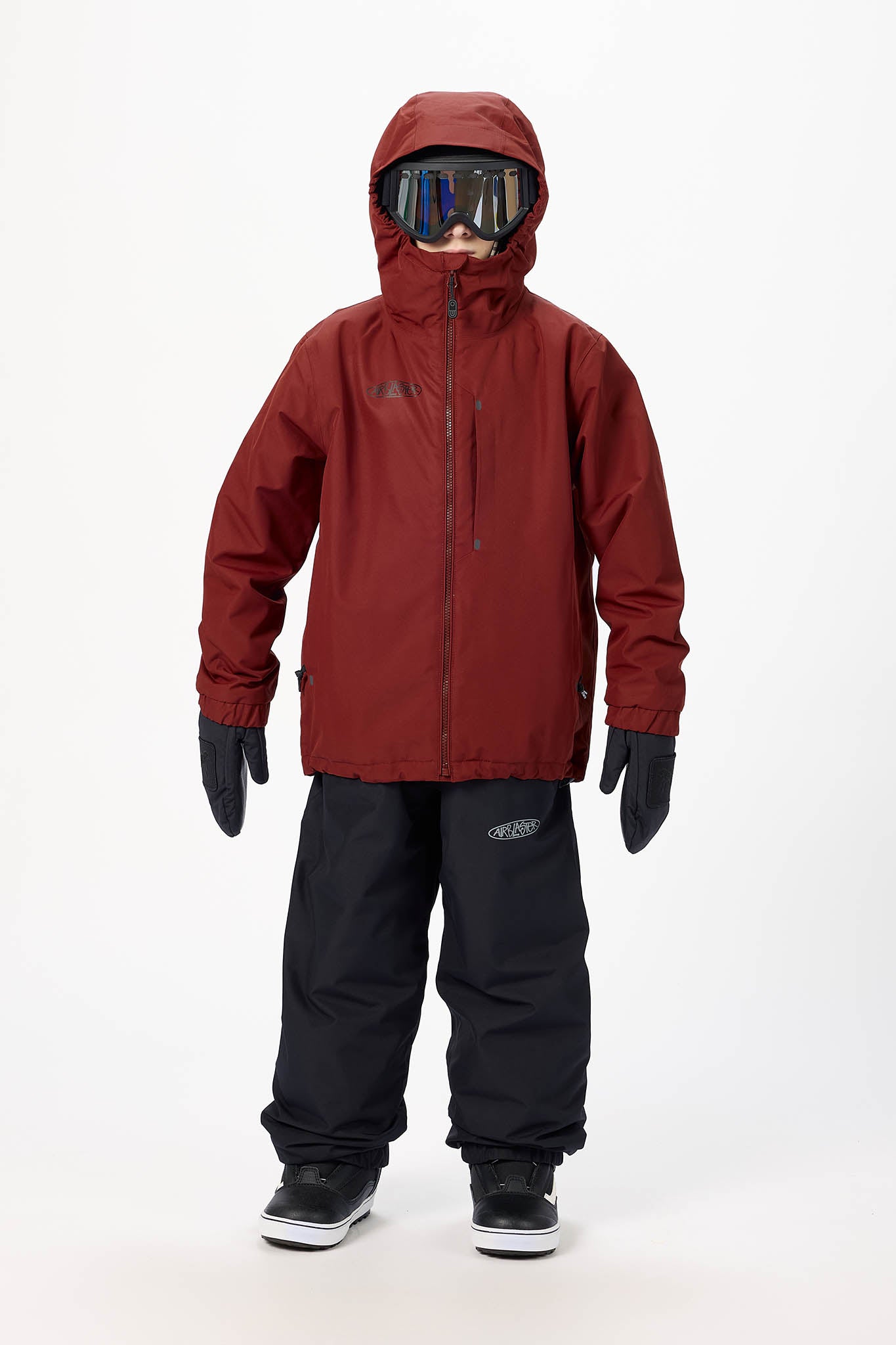 A child model wearing a burgundy hooded snowboard jacket, black snow pants, black gloves, and goggles, standing against a plain white studio background.